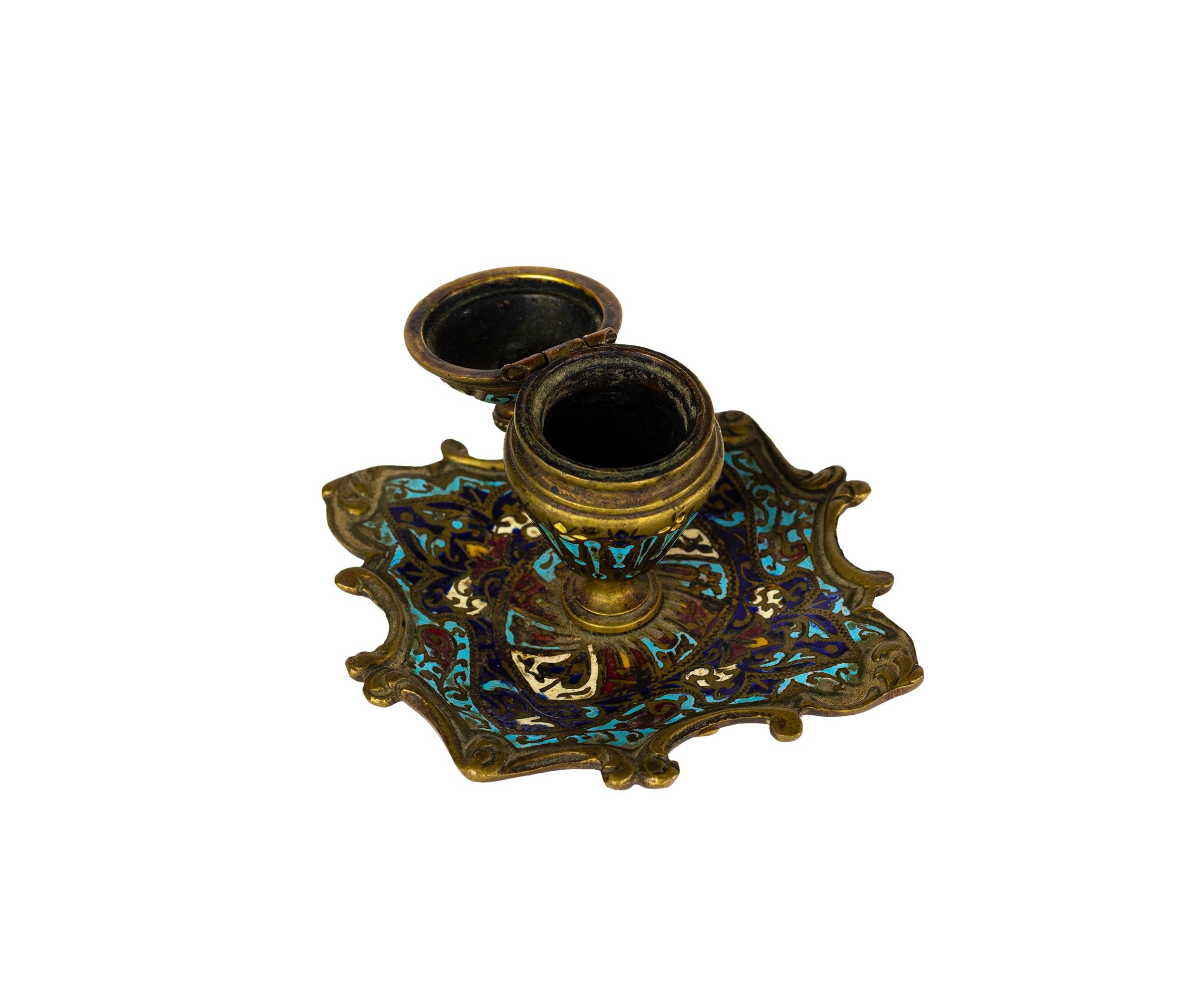 Tintero francés de esmalte champlevé del siglo XIX, creado en el opulento estilo de Napoleón III. 

Elaborado en bronce dorado con esmalte policromado finamente detallado en tonos turquesa, azul oscuro, rojo, amarillo y dorado, el tintero presenta