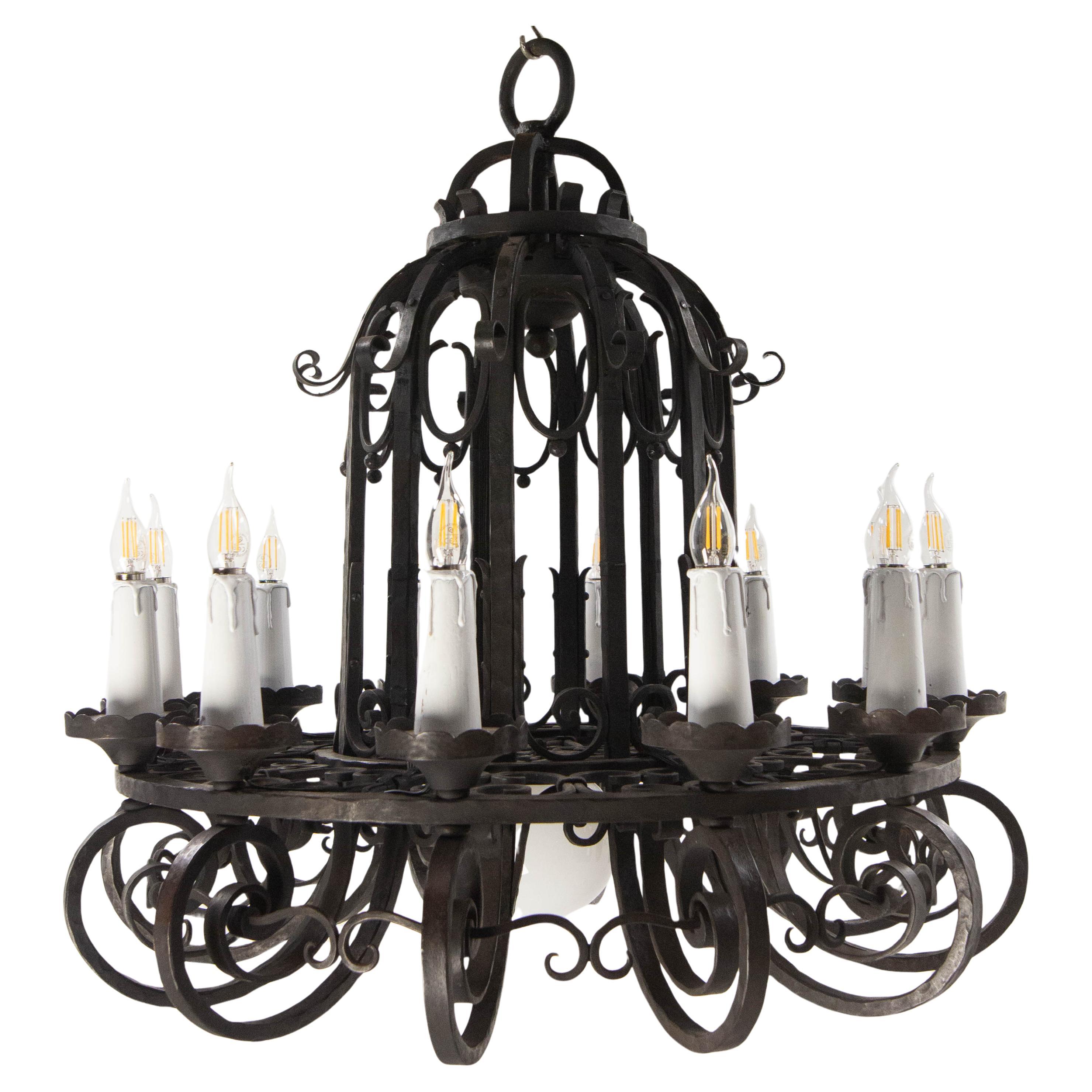 Remarkable thirteen-lights wrought-iron chandelier.
Ceiling pendant with twelve bulbs on wooden candle-style holders and an opaline lamp above the pendant light.
It is this last lamp that earned this chandelier the name “Lustre à la Perle” (Pearl