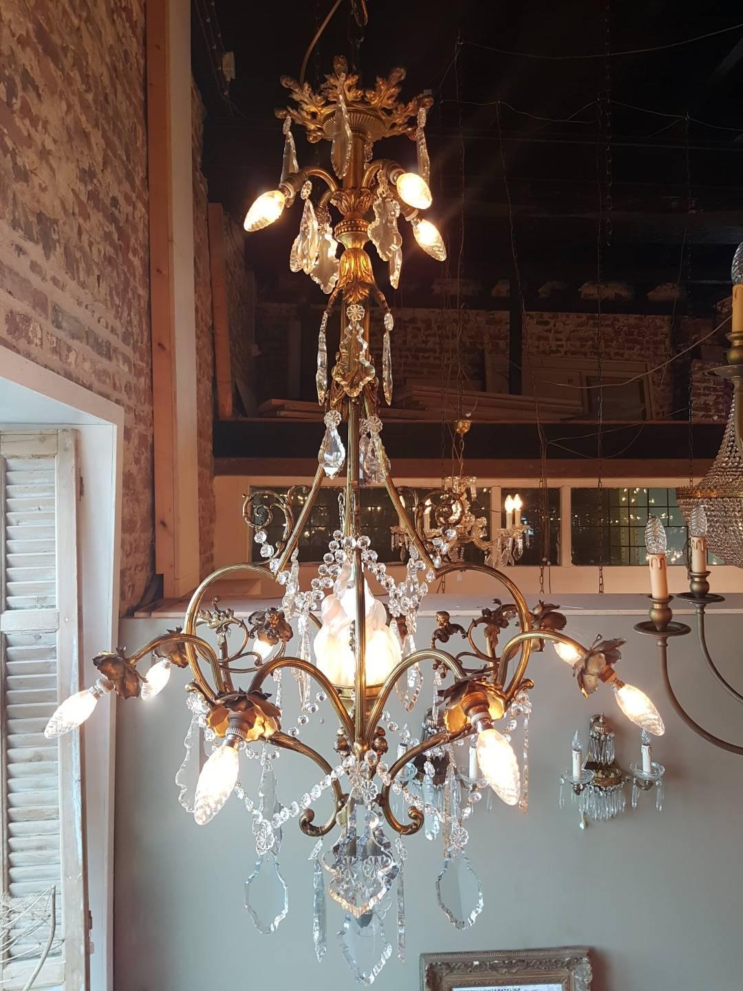 Original French Chandelier with four lights in the top, eight lights are bending down covered with delicate leaves. One light in the middle covered by a big frosted Flame of Glass. In the center under the Flame are four Angels of Bonze and four