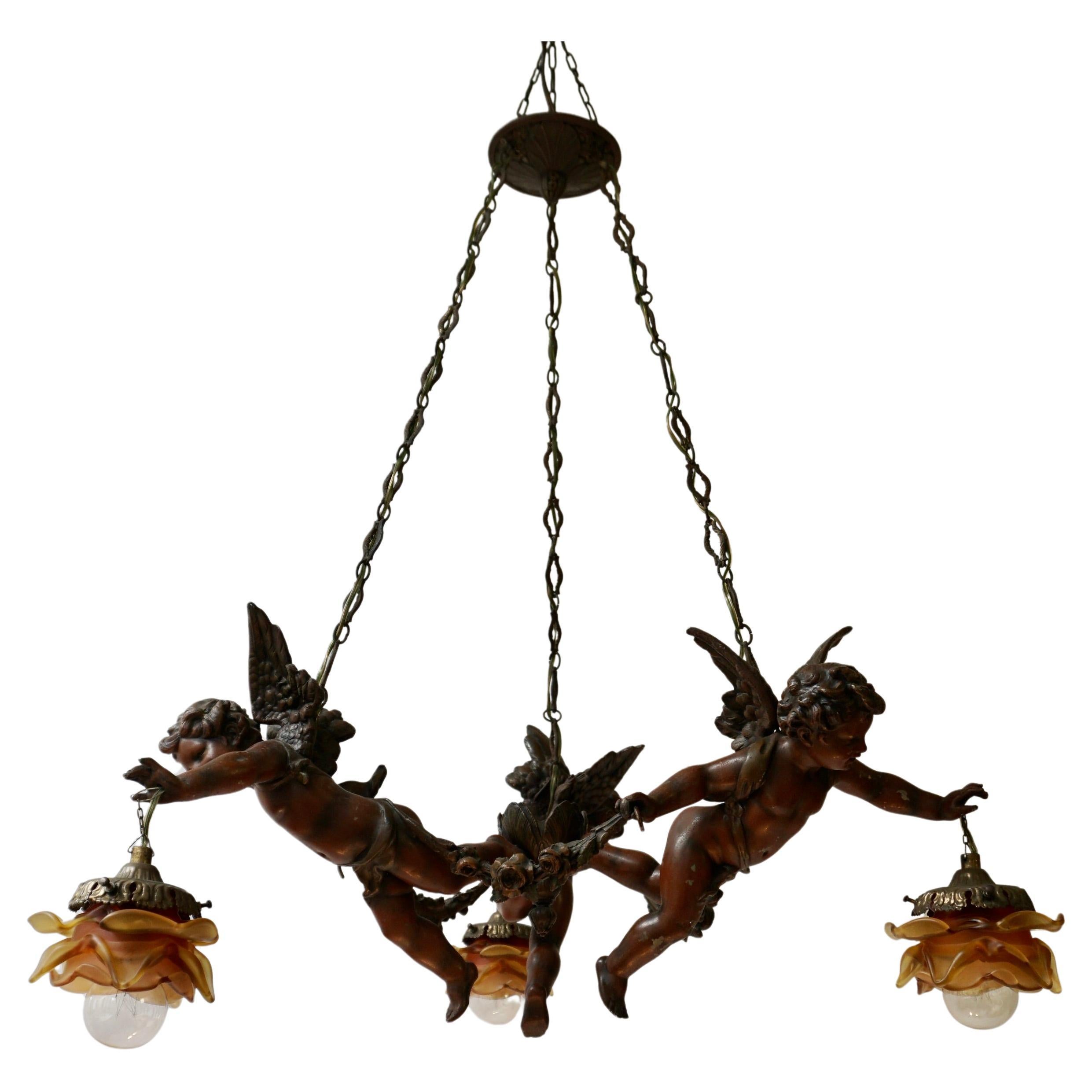 A French three-light chandelier from the 19th century, with ribbons and cherubs holding the shades. Born in France during the early 20th century, this three-light chandelier features a ribbon-tied canopy, supporting profiled links. The lower section