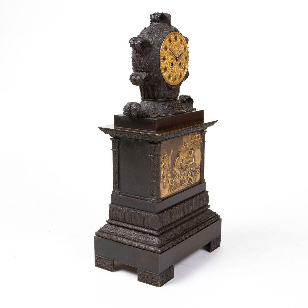 Französische Kaminsimsuhr aus Bronze von Karl X. / Spätimperium, gefertigt aus dunkelpatinierter Bronze mit vergoldeten Details.
Reichhaltig verziertes, rundes, vergoldetes Zifferblatt mit römischen Ziffern und floralen Motiven.
Das Gehäuse ist mit