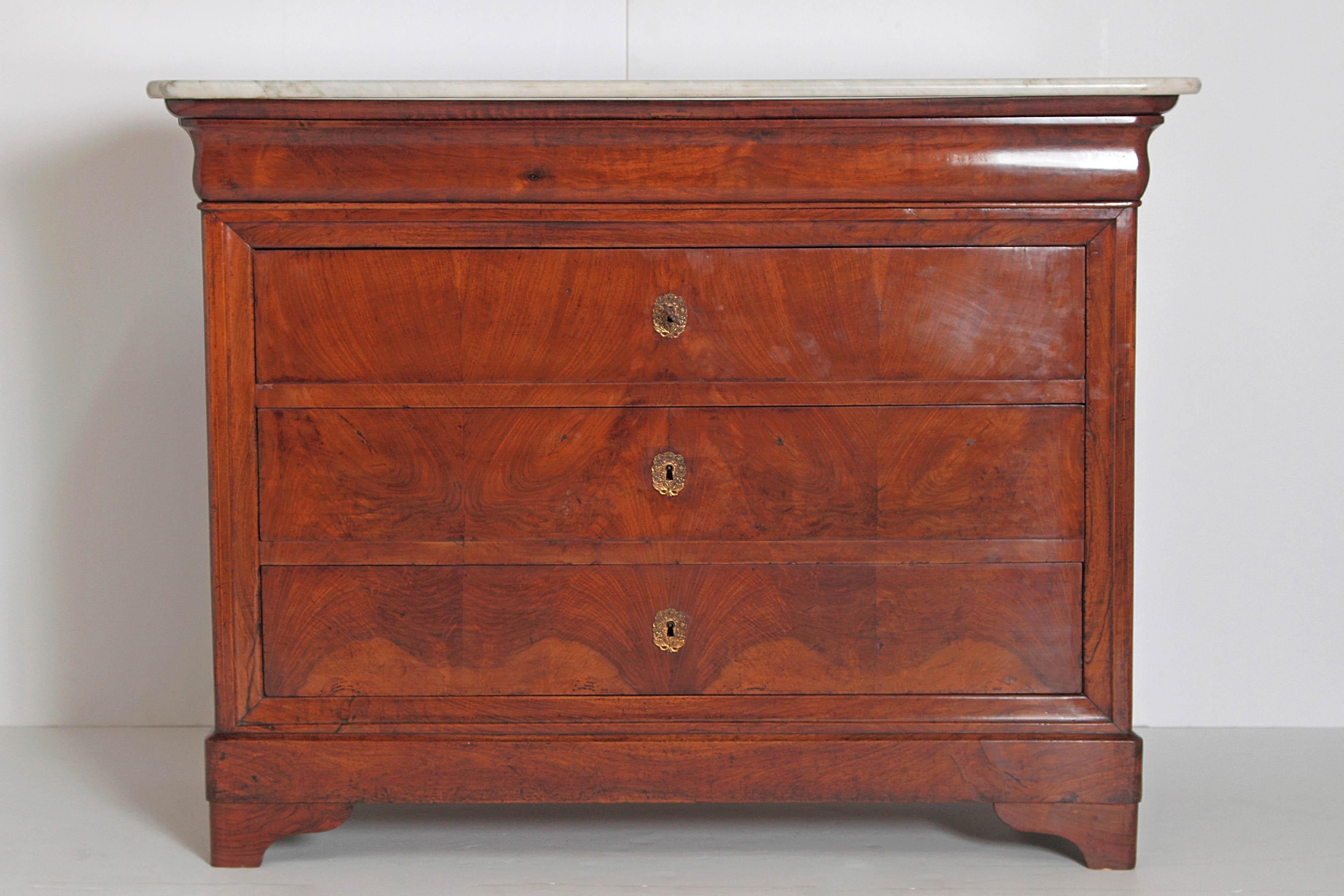 A 19th century French Charles X chest of drawers or commode with simple yet elegant lines. It has a white marble top with a base of mahogany with a shaped frieze over three drawers. Each drawer has its own working lock and comes with one key, 19th