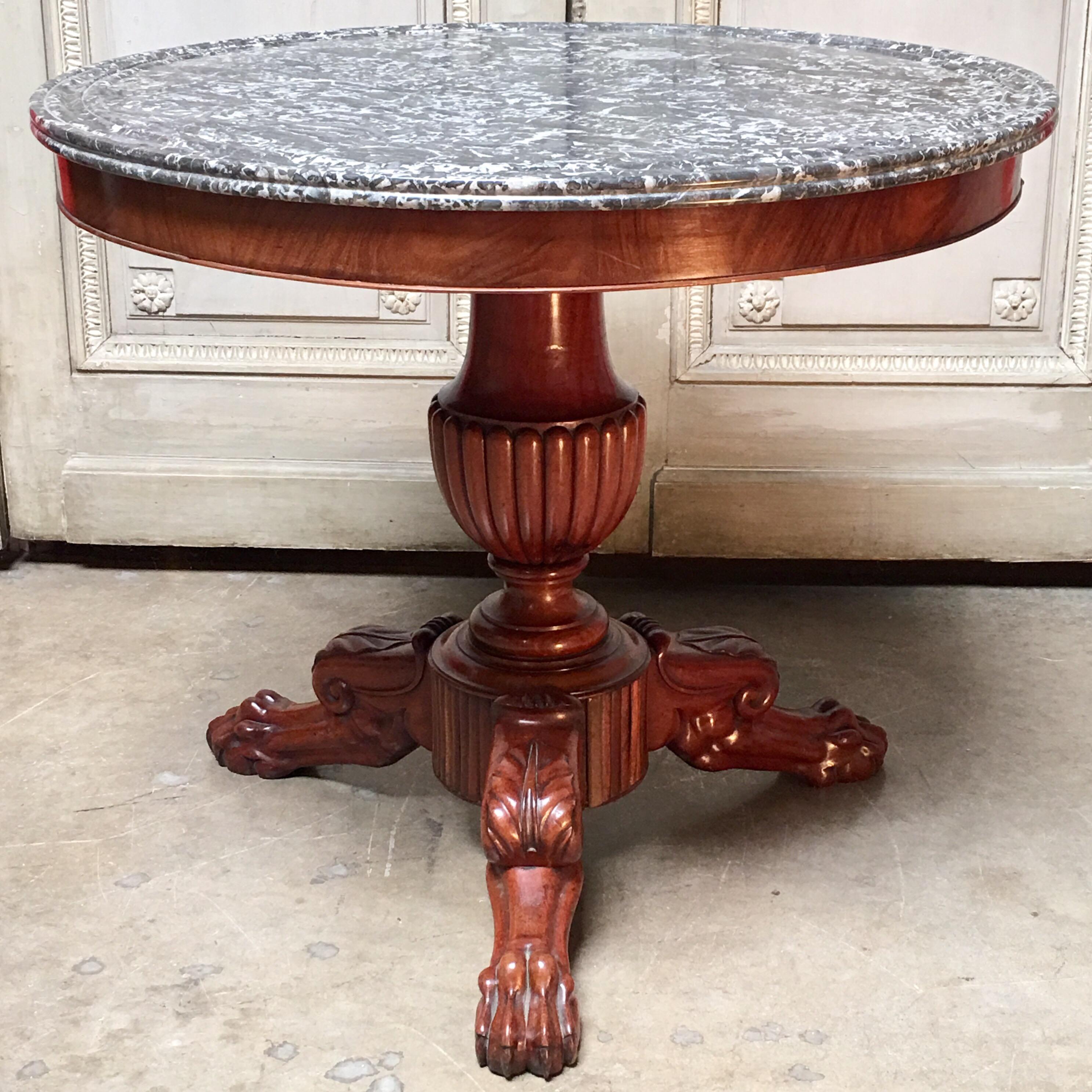 An early 19th century French Charles X mahogany table with a dark grey and white veined marble top. This handsome,  sculptural table has a carved urn shaped pedestal with acanthus leaf and claw foot feet. 