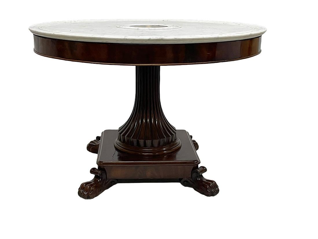 French Charles X mahogany table with white marble top, ca 1840

A French 19th century Charles X table with a white marble top, with double rings of reliefs and with marble in mosaic, pieces set in a star shape in the centre.
The table has a fluted