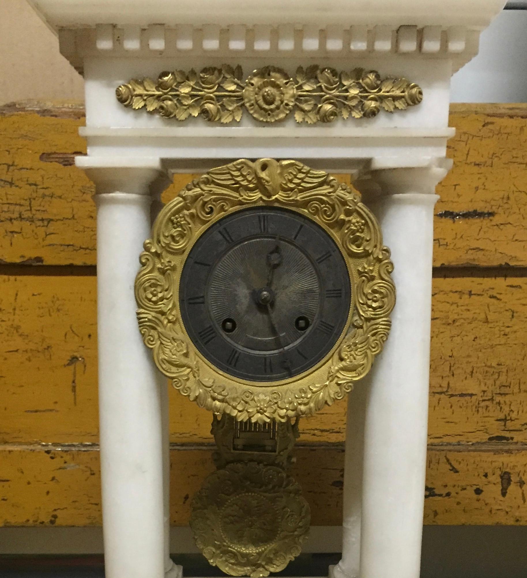 With tasteful embellishments of brass on the pure marble surface, this Charles X mantel clock is restrained and most attractive. The time piece is distinctly architectural in form, a piece inspired by the classical Greek structures so revered during