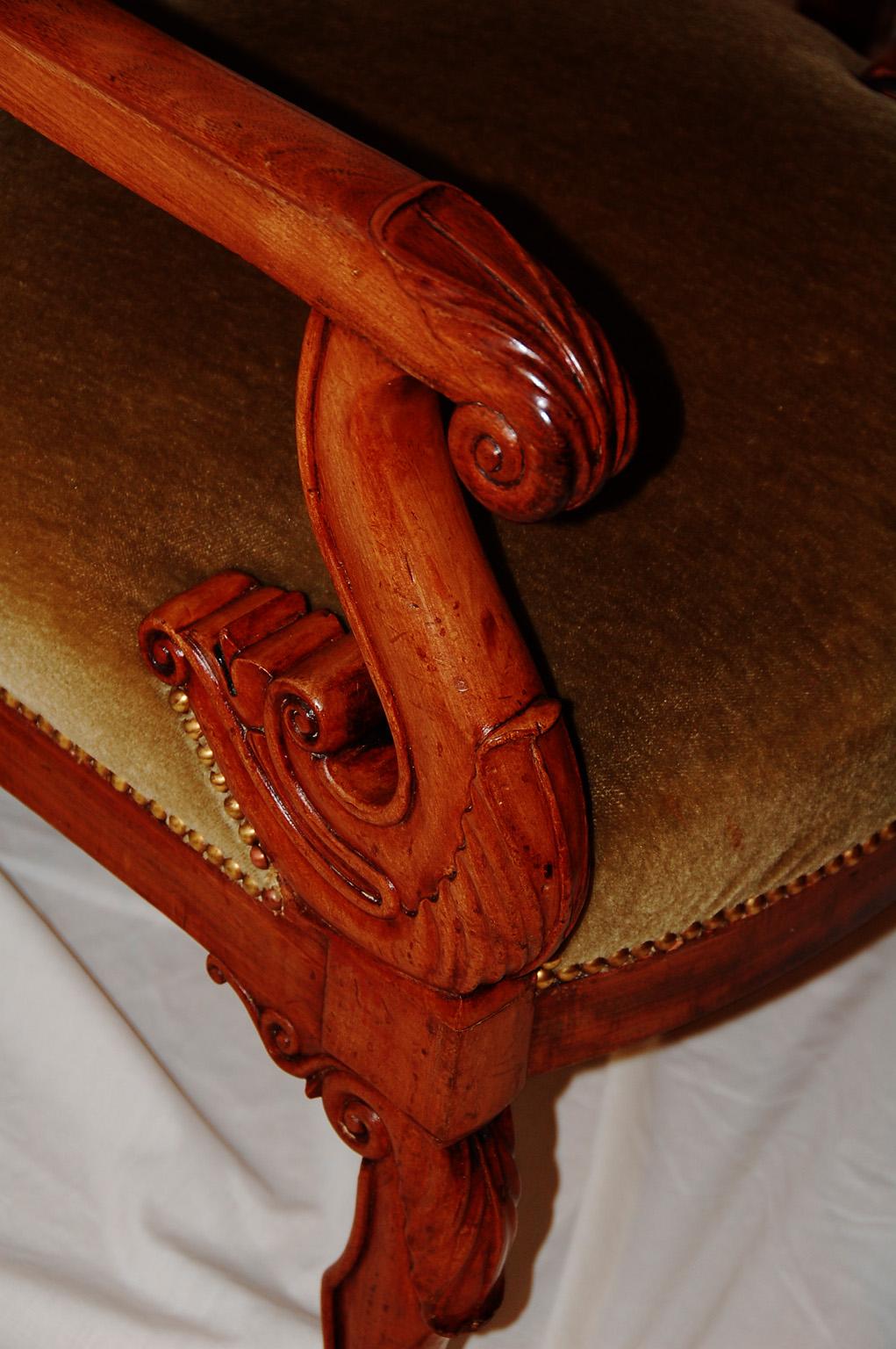 French Pair of Charles X period walnut fauteuils. This pair of upholstered armchairs have carved arms and legs with anthemion and leaf motifs. The warm butterscotch color of the walnut and the rounded edges of the frame are typical of the Charles X