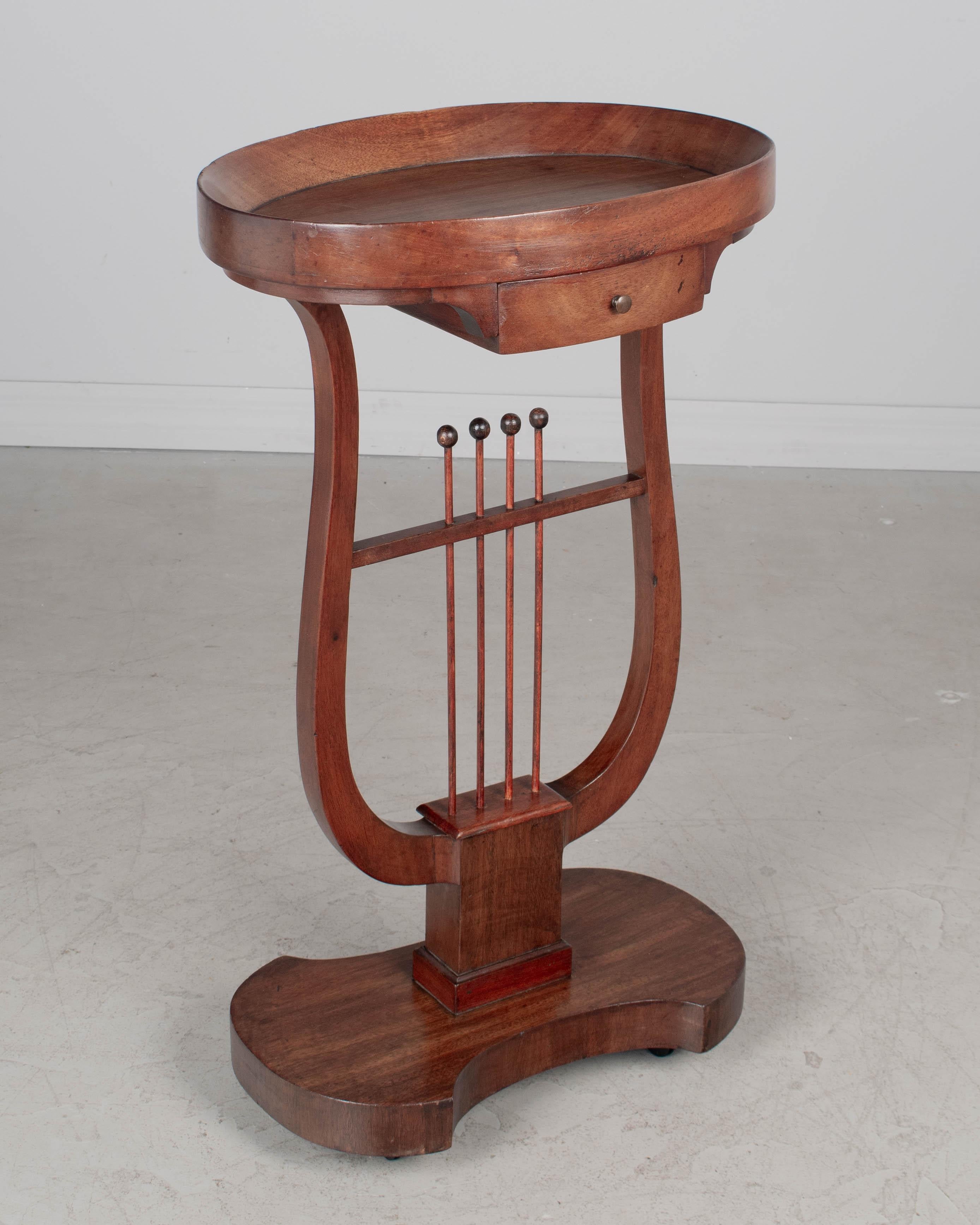 Guéridon ovale de style Charles X en acajou massif et placage d'acajou. Une belle table d'appoint avec un piédestal en forme de lyre et un plateau. Petit tiroir avec bouton en laiton. Belle taille pour une utilisation comme table à boissons ou table