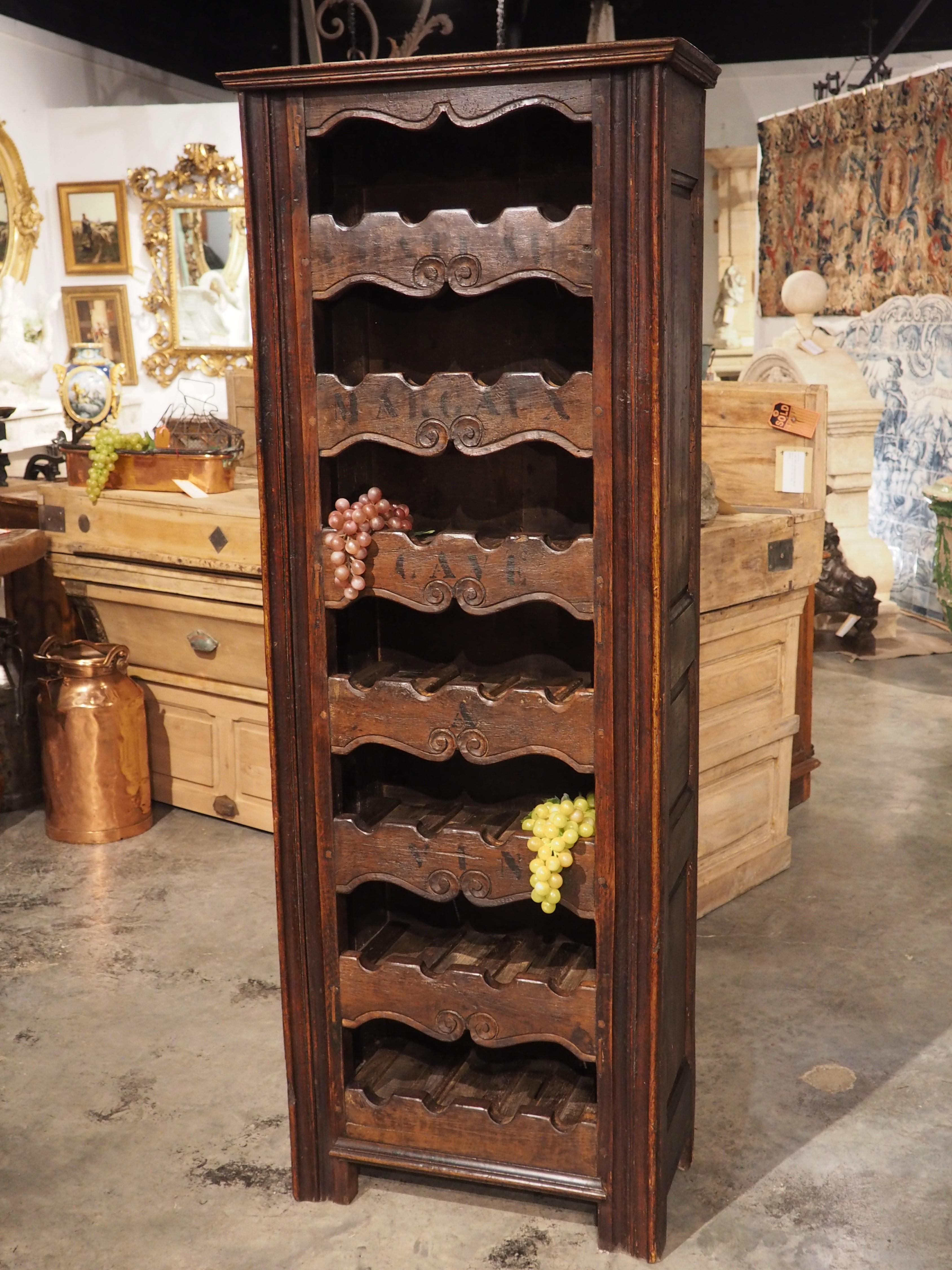 A towering cave a vin wine bottle carrier from France, sections of the wood were repurposed from 19th century furniture, most likely a chiffonier or country clock case. The piece has been made with a total of seven wine racks each with a four bottle