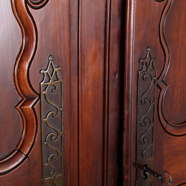 A grandly-proportioned French cherrywood-and-chestnut two-door armoire, the two-panel doors with elegantly carved details, and accented with an inlaid fruitwood star at the top.

The armoire retains all its original hardware including massive