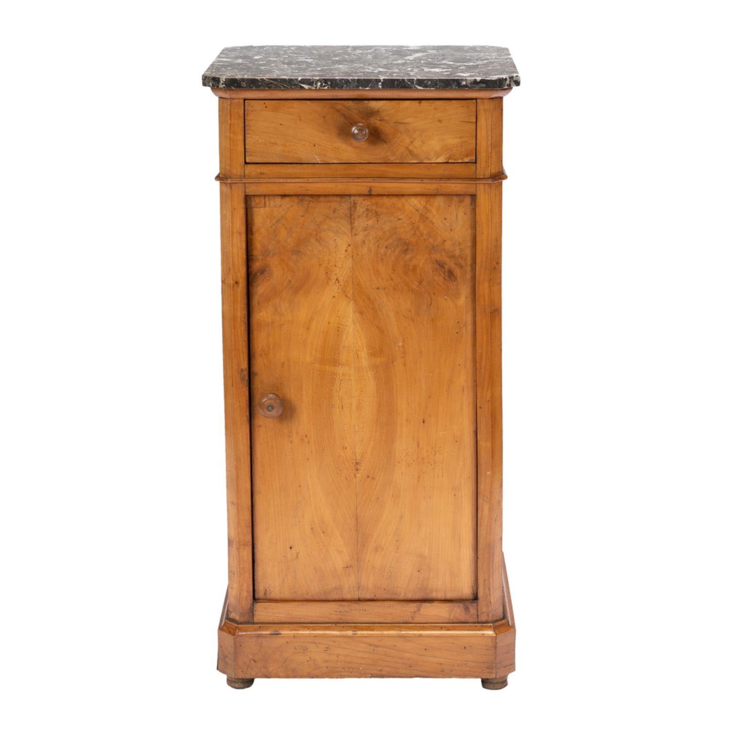 French cherry wood chevet with original gray & white Saint Anne marble top. The cabinet has one drawer over a single long door, with turned cherry knobs. The commode rests on a square molding cut corner base on castors
France, 1830-45.