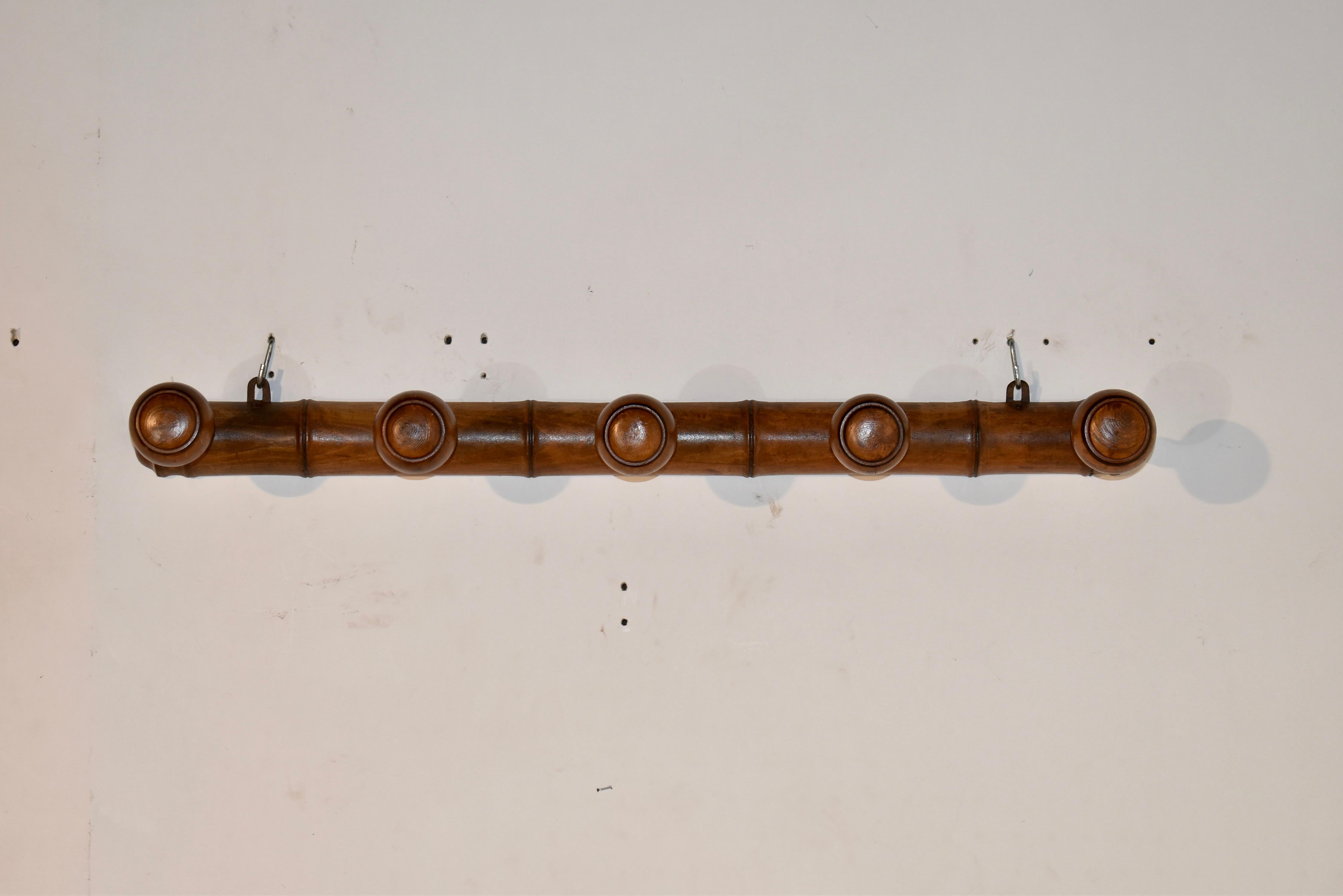 Five peg hat or coat rack from France, made from cherry, circa 1920. The back of the rack is designed with raised molding, to give a look of bamboo, and it has five hand turned lollipop pegs for hanging hats or coats. These are also great in a