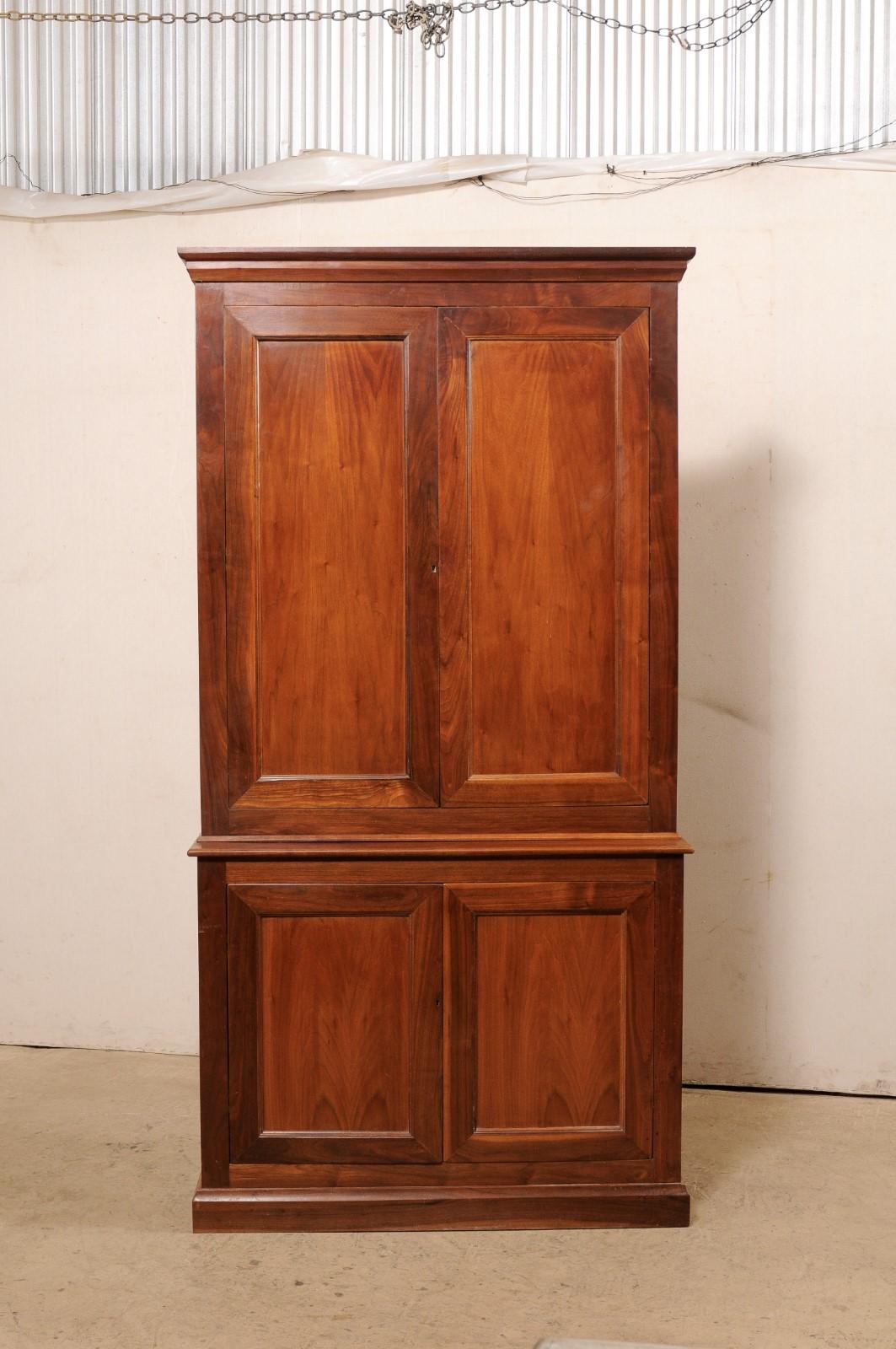 A French tall cabinet of cherry wood, designed in clean, linear lines, from the mid 20th century. This mid-century cabinet from France stands just over 7.5 feet in height and has a more slender depth, of only 15