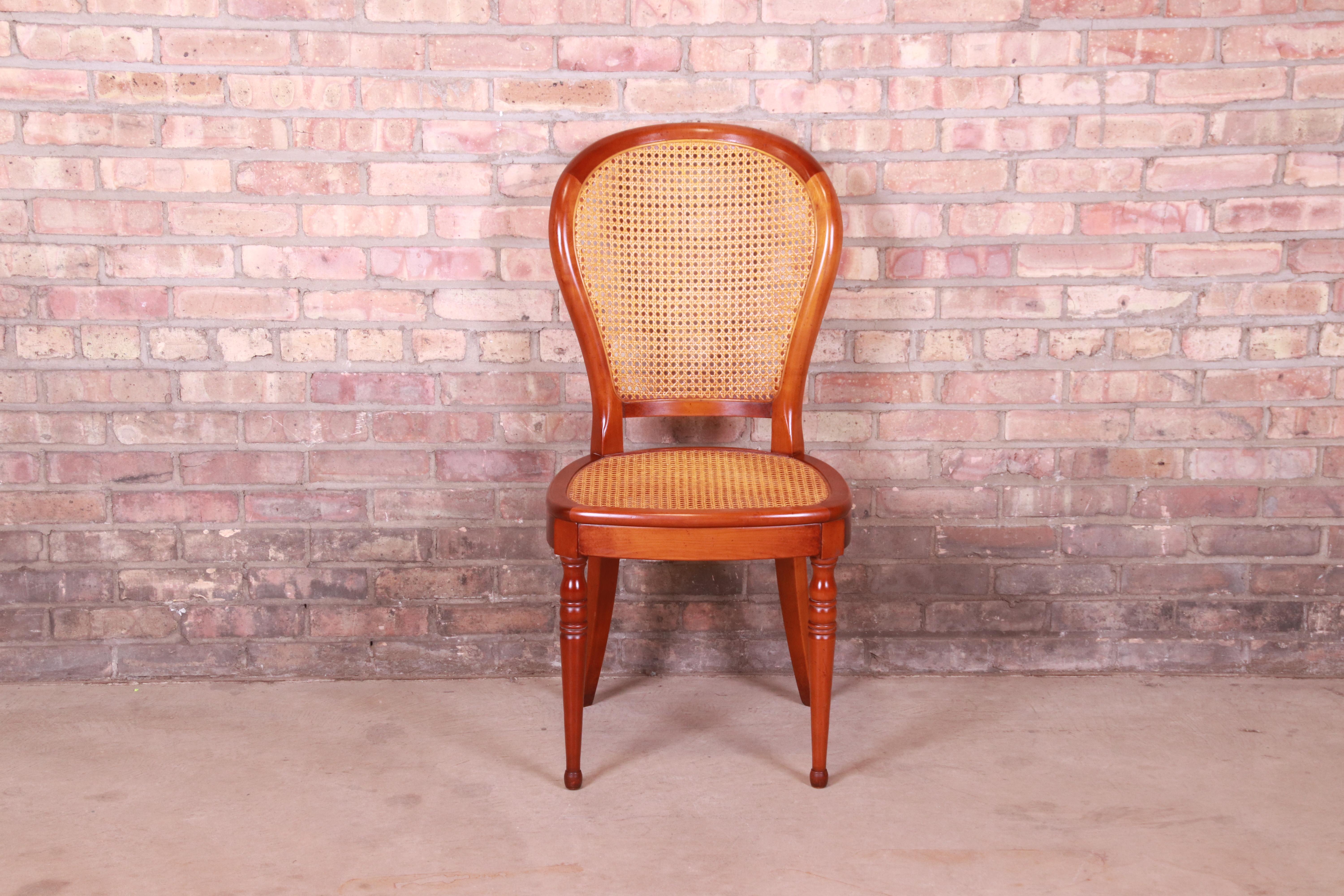 A gorgeous French balloon back side chair or desk chair

Attributed to Grange

France, late 20th century

Cherry wood, with turned legs and caned seat and back.

Measures: 18.5