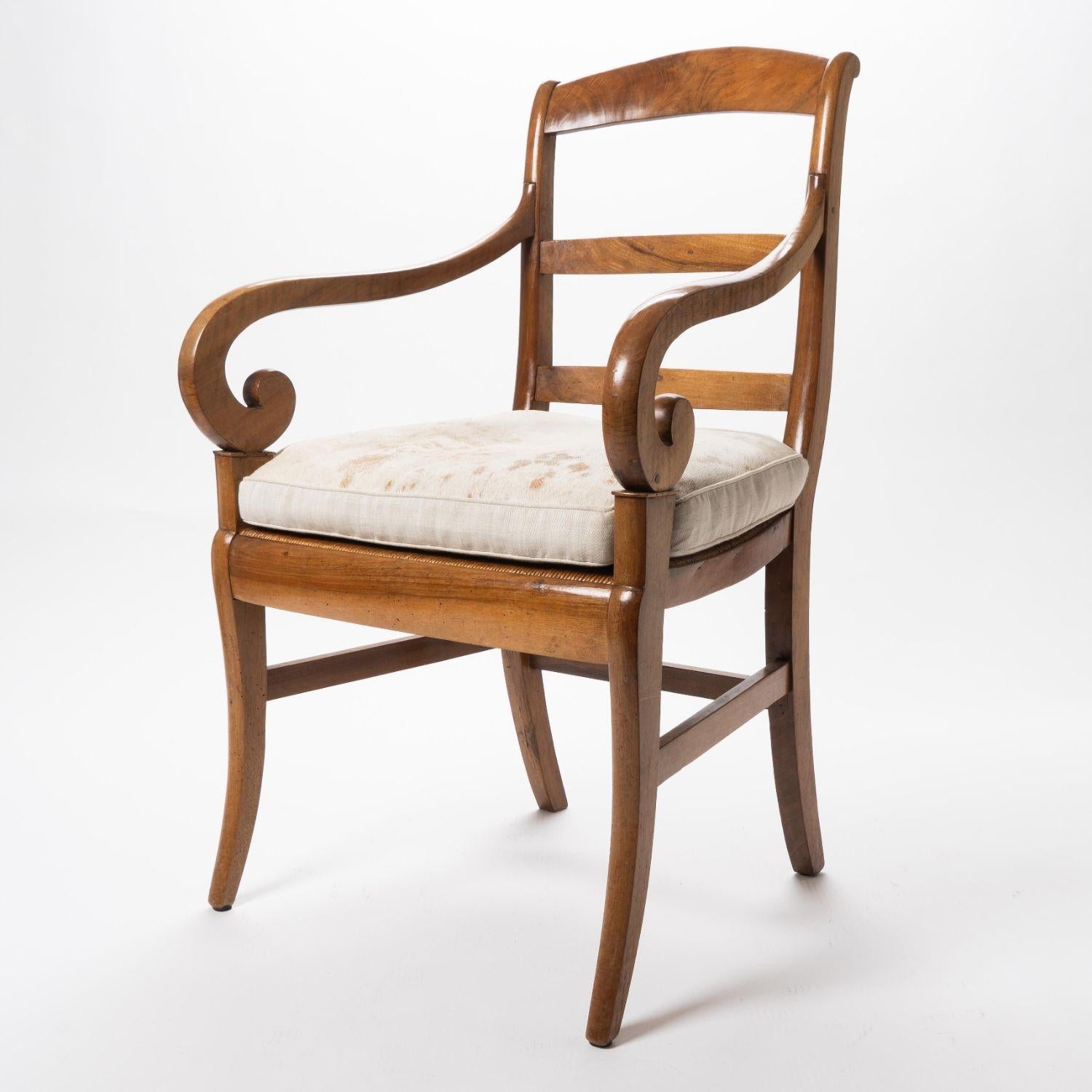Cherry wood fauteuil (open armchair) with a finely woven natural rush seat. The ram’s horn arms are supported by a plinth above the seat frame, and the front, pseudo-sabre legs. The legs are joined by a boxed stretcher, and the seat is fitted with a