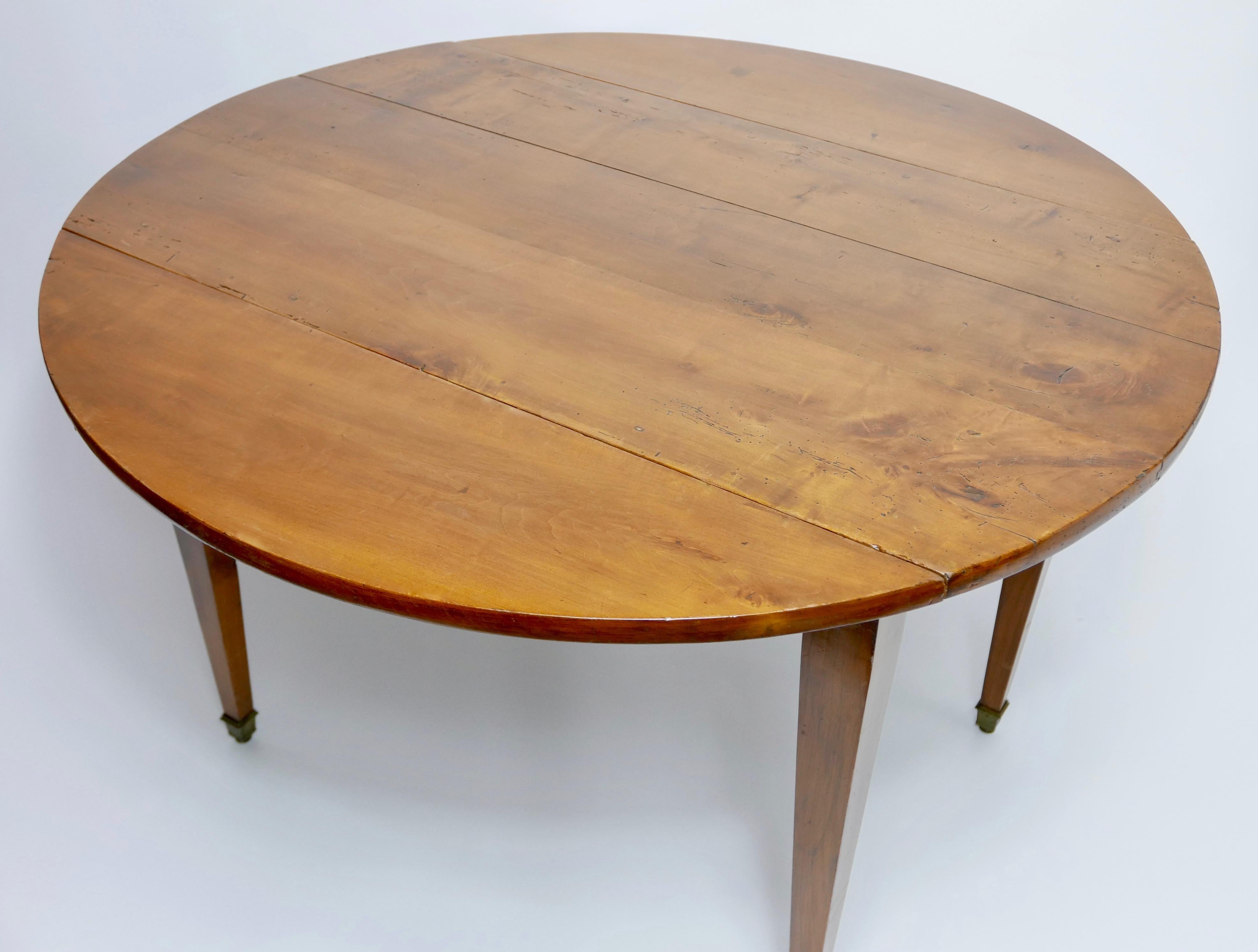 French Provincial solid cherrywood drop-leaf table with square tapering legs terminating with brass sabots. The 1