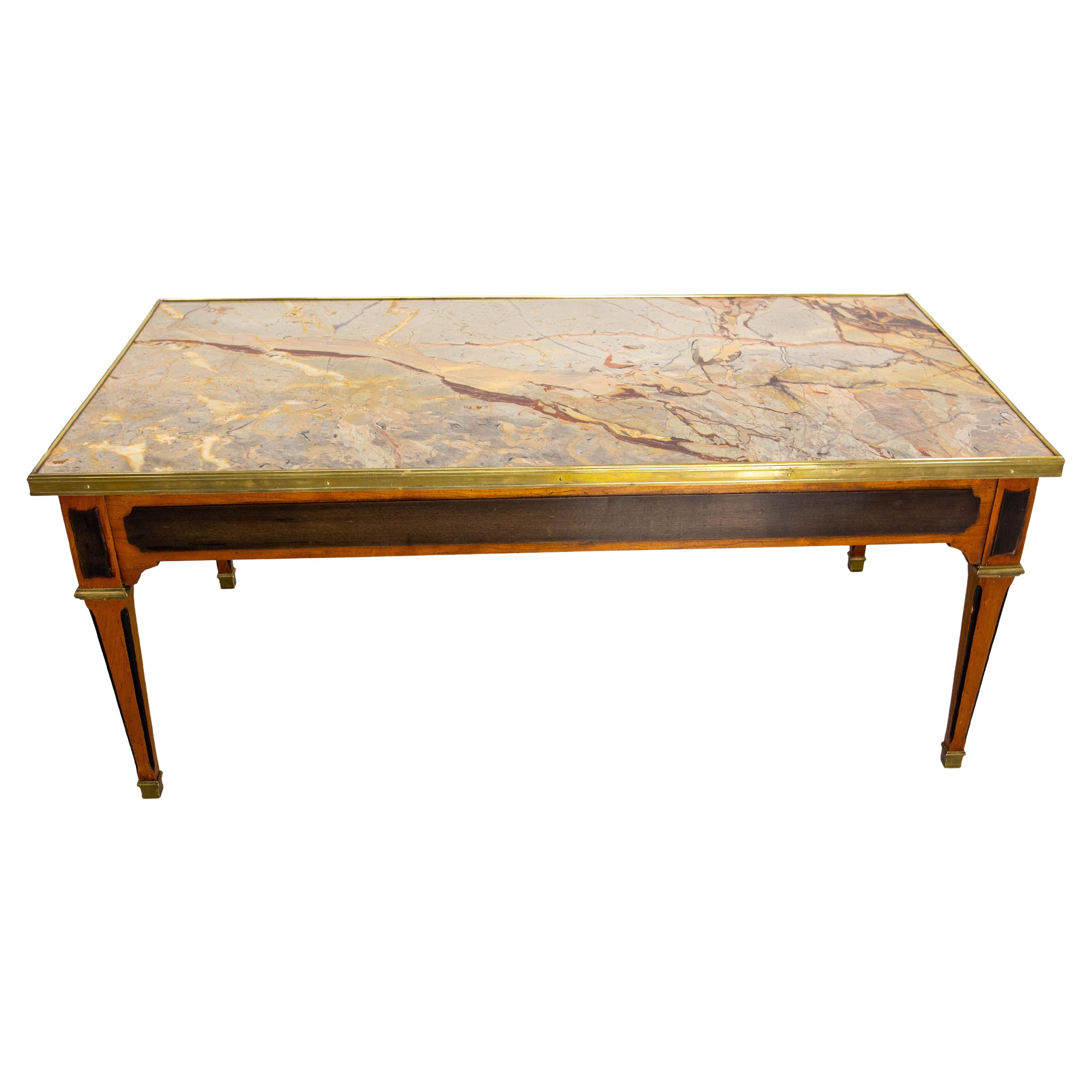 French midcentury coffee table with marble top. 
The marble is held in place by a brass belt. The massive cherry wood has been carved and stained to give it this classic style.
The colors of this marble are well balanced. The dominant cream color is