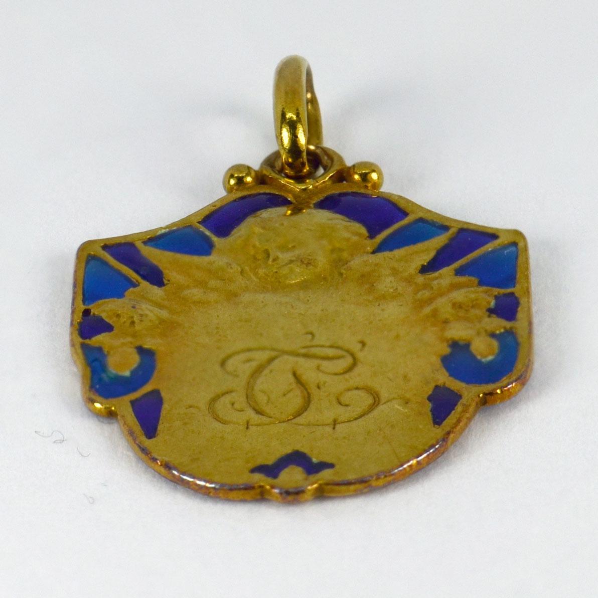 An 18 karat (18K) yellow gold pendant designed as a medal depicting a cherub with a blue plique-a-jour surround. Engraved to the reverse with a monogram of TC/JC and the date ‘23/12/23’.  Stamped with the eagle’s head for French manufacture and 18