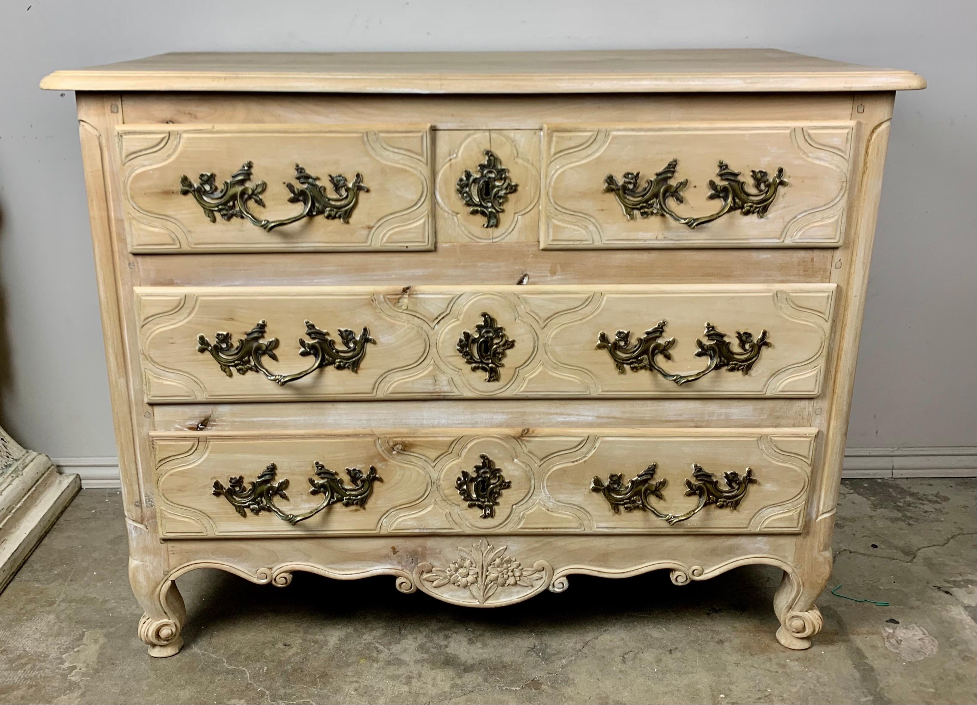 French Louis XV style three drawer dresser with cast brass hardware pulls and key holes. The chest stands on four cabriole legs with rams head feet and a graceful scalloped bottom. The chest has a beautiful natural wood finish.