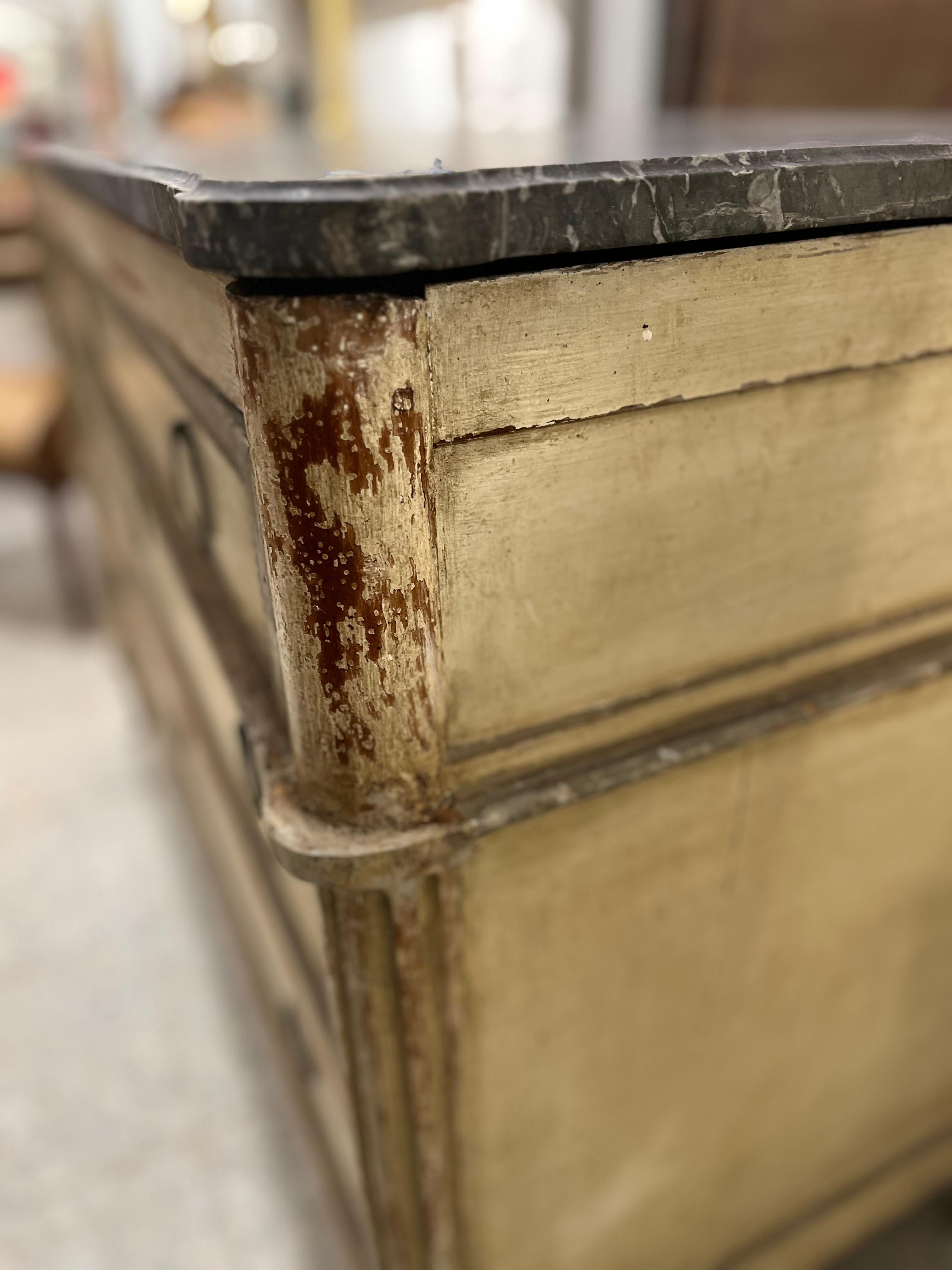 Commode Directoire française, fin XVIIIe ou début XIXe siècle, en bois sculpté, peint et patiné, avec un plateau en marbre gris, des cannelures sur les côtés et des sculptures géométriques encadrant les trois tiroirs, celui du haut étant légèrement