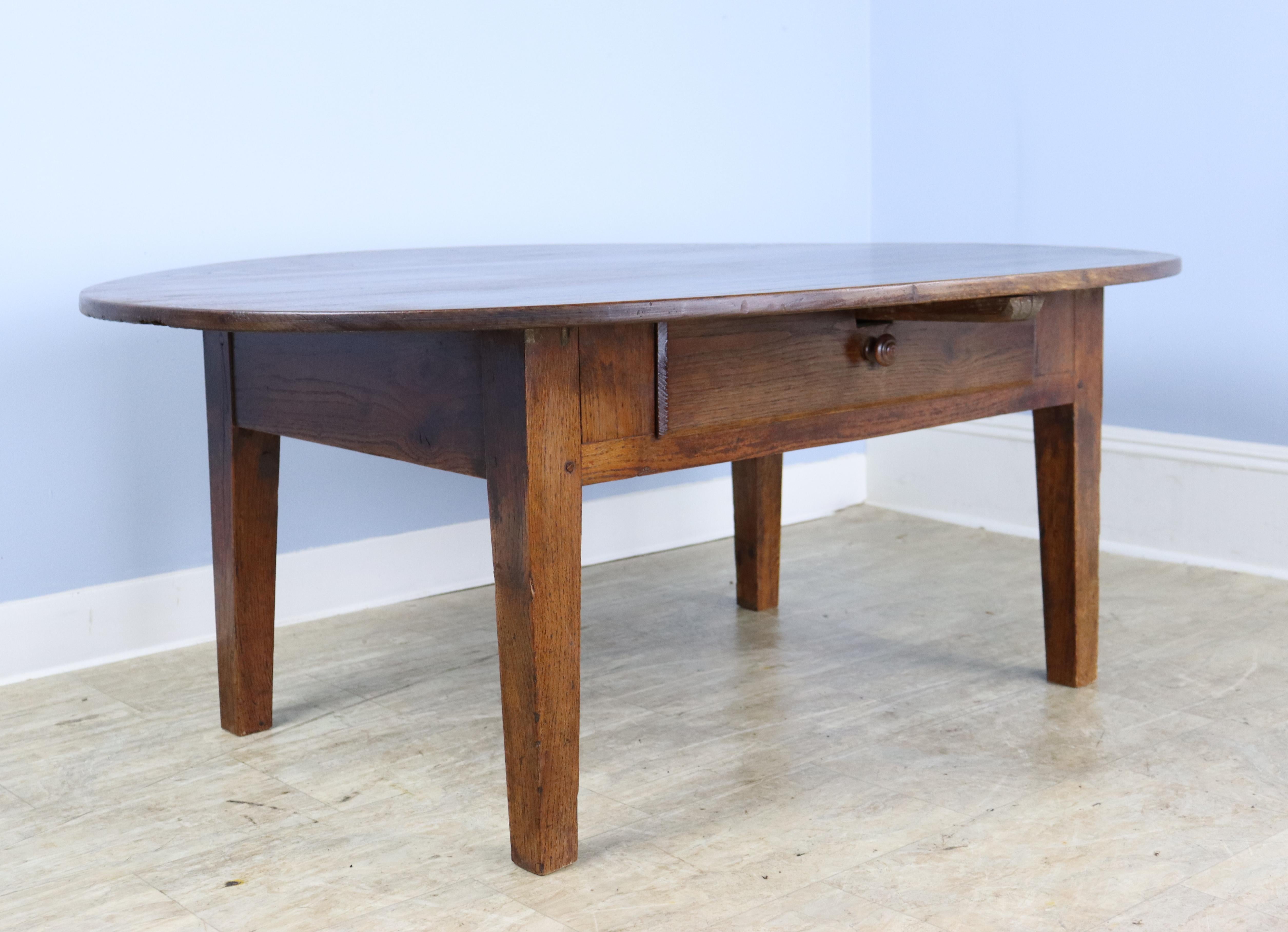 A simple, lustrous, and warmly toned oval chestnut coffee table from France. The top is large, well grained, and polished to a glow. very good chestnut grain. There is a small drawer in the apron.