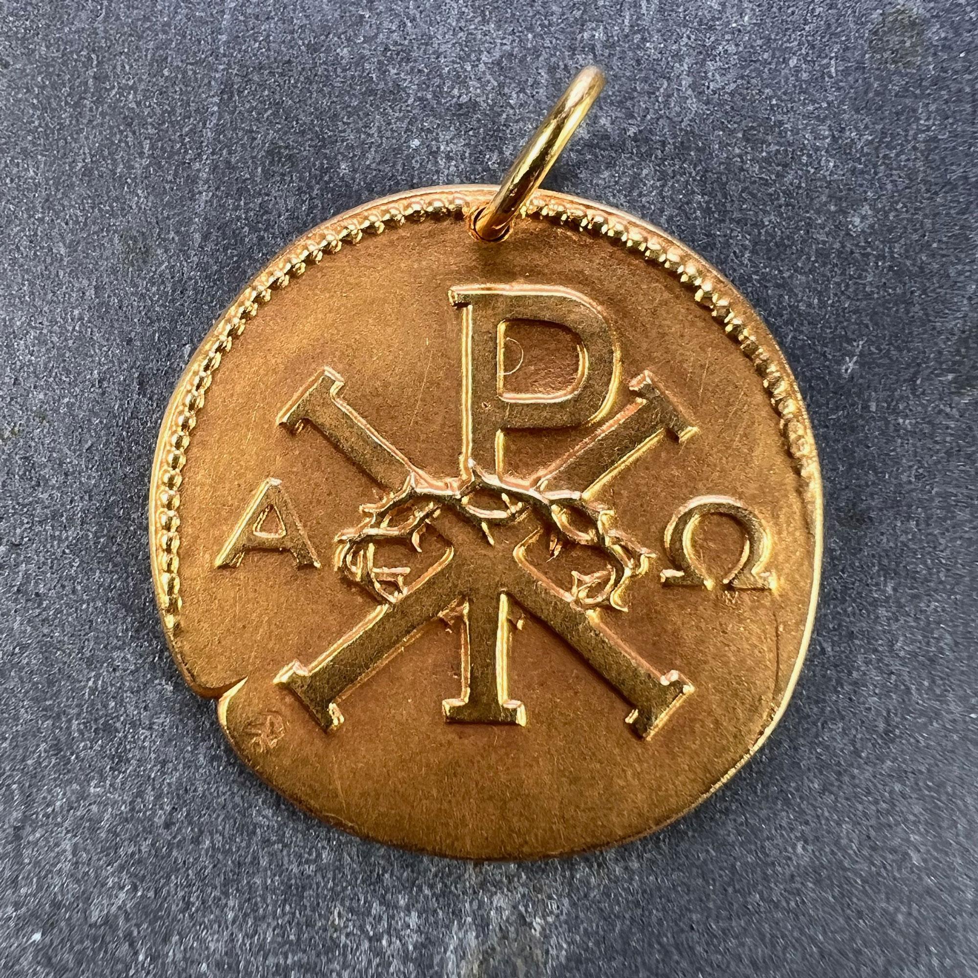 A French 18 karat (18K) yellow gold religious medal pendant depicting the symbol for Chi Rho entwined with the crown of thorns, surrounded by the letters Alpha and Omega (all being symbols of Jesus Christ to one side. 

The reverse depicts the head