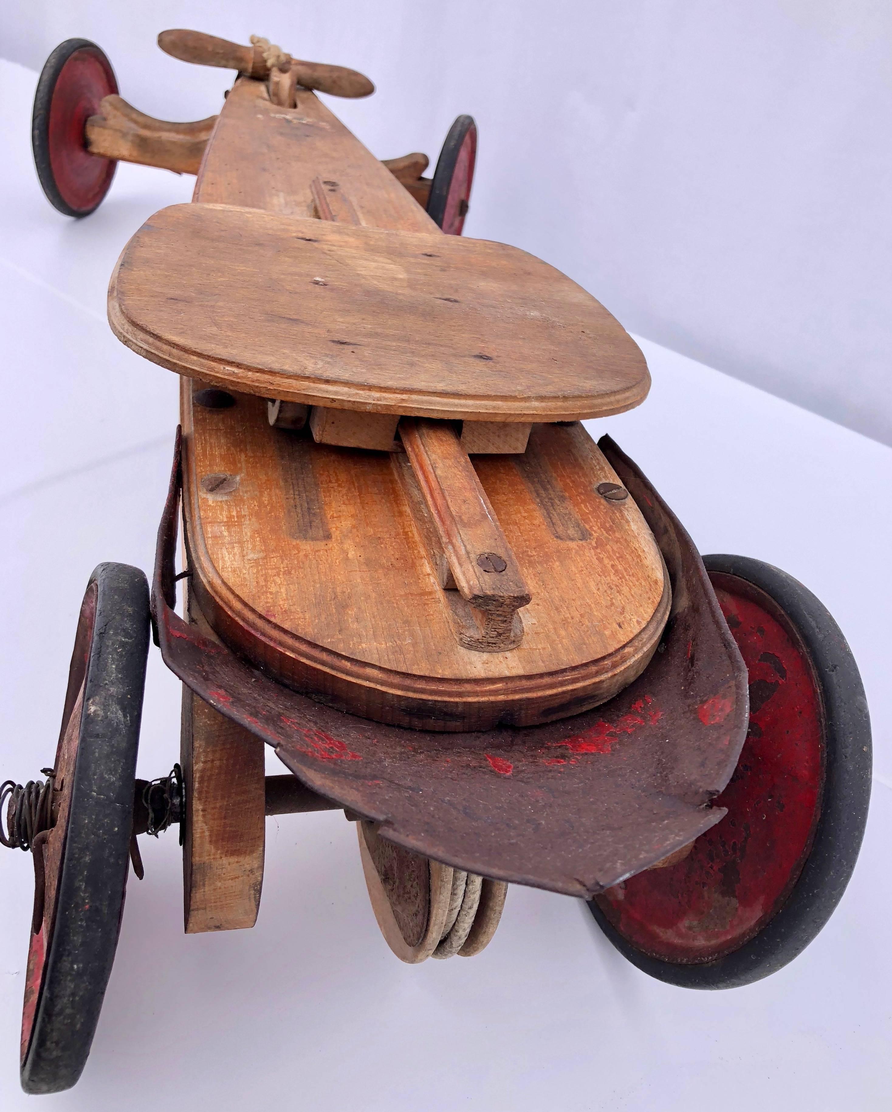 This is a child's French AUTO - SKIFF four wheel wood and metal vehicle with sliding seat, which is used by pulling the wooden handle toward you much like a rowing machine. It was made by MFA (manufacture française d'ameublement) St Etienne and sold