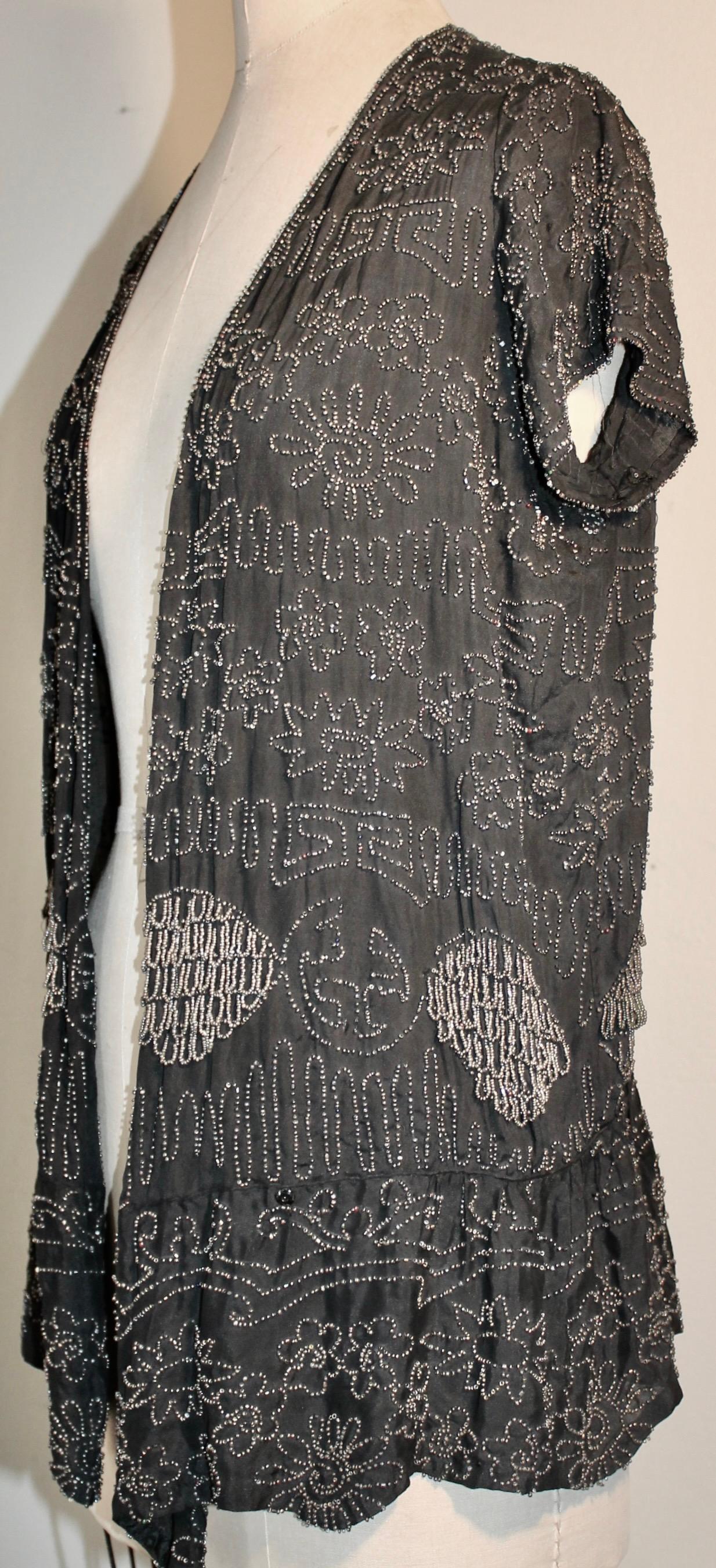 Brodé principalement de perles d'argent dans un design Chinoise, sur un fond noir semi transparent. 
