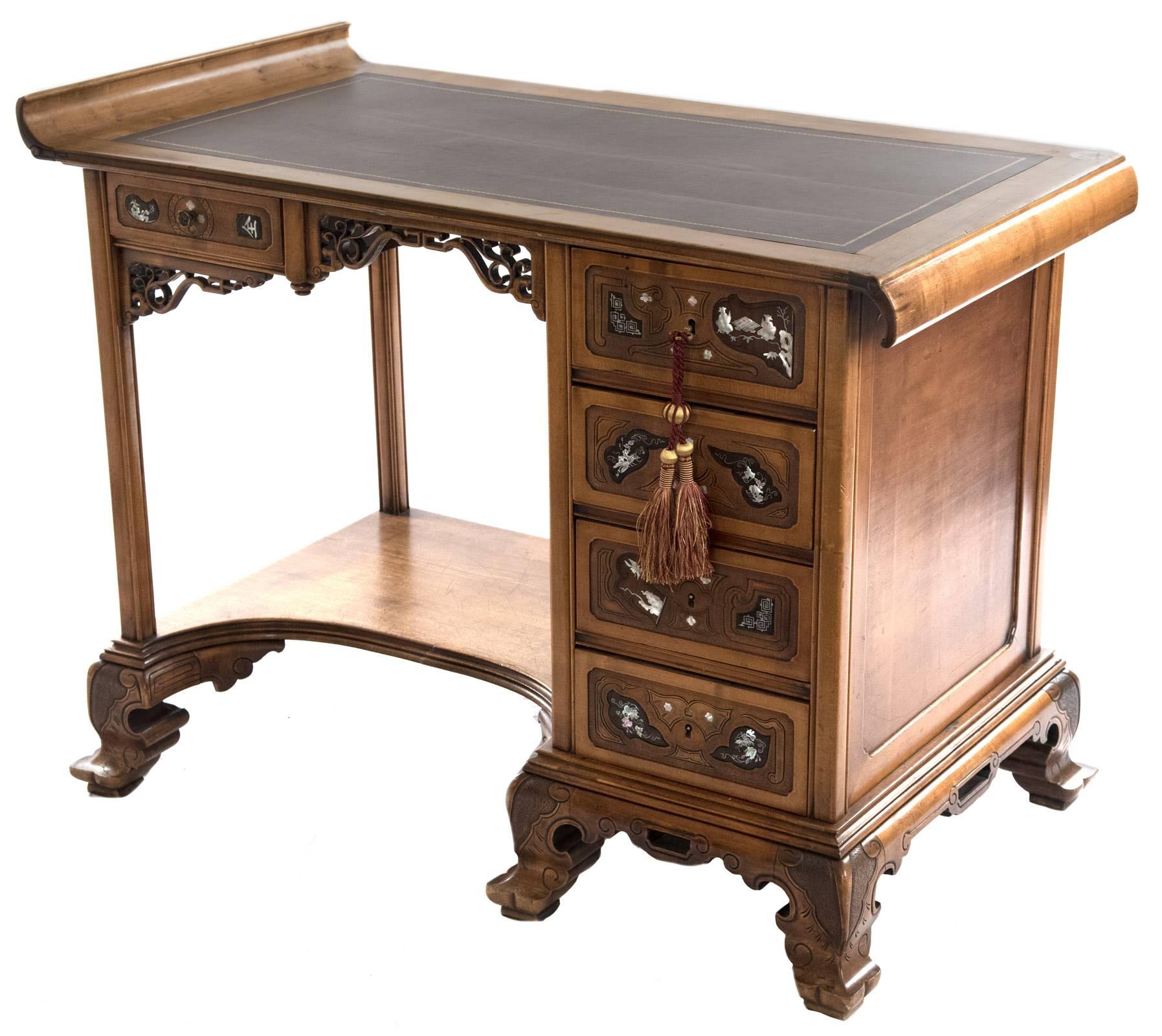 A carved walnut desk inspired by Asian forms for which Parisian cabinetmaker Gabriel Viardot (1830-1906) was renowned in the late 19th century. The desktop has up-curved and down-curved ends and is fitted with a leather pad, above an apron with a