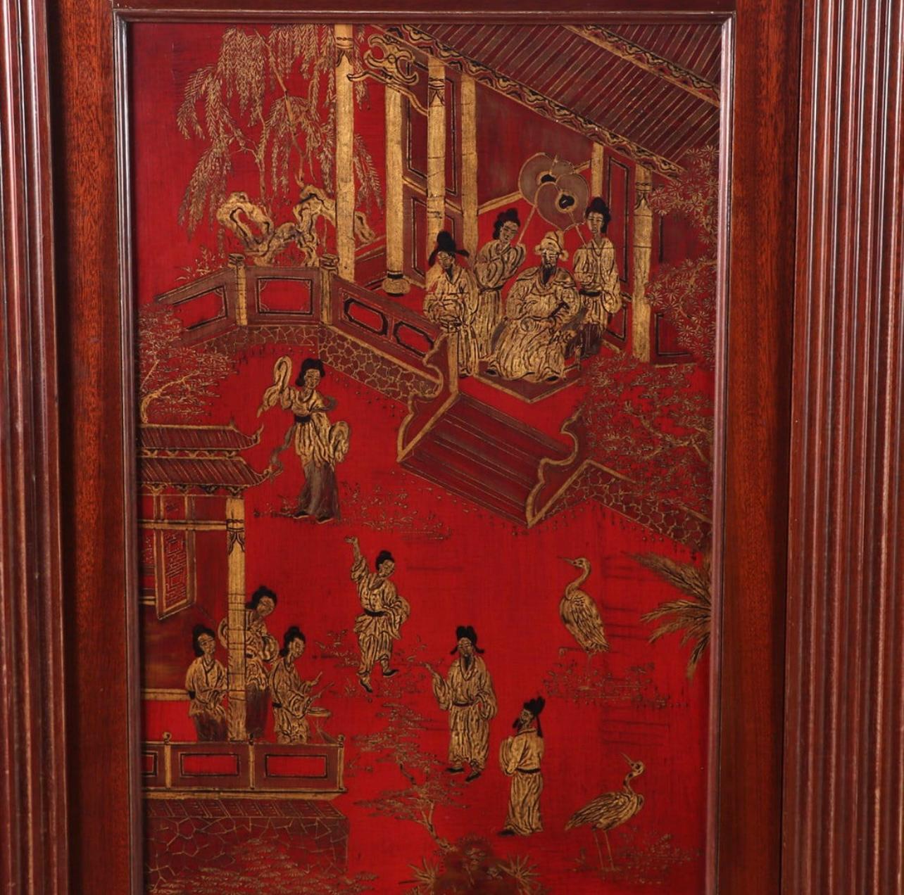 Une grande armoire de style chinoiserie française, avec deux portes.  Ce meuble massif a de belles proportions et présente de belles peintures de style export chinois représentant des paysages et des scènes de personnages en or sur un fond rouge