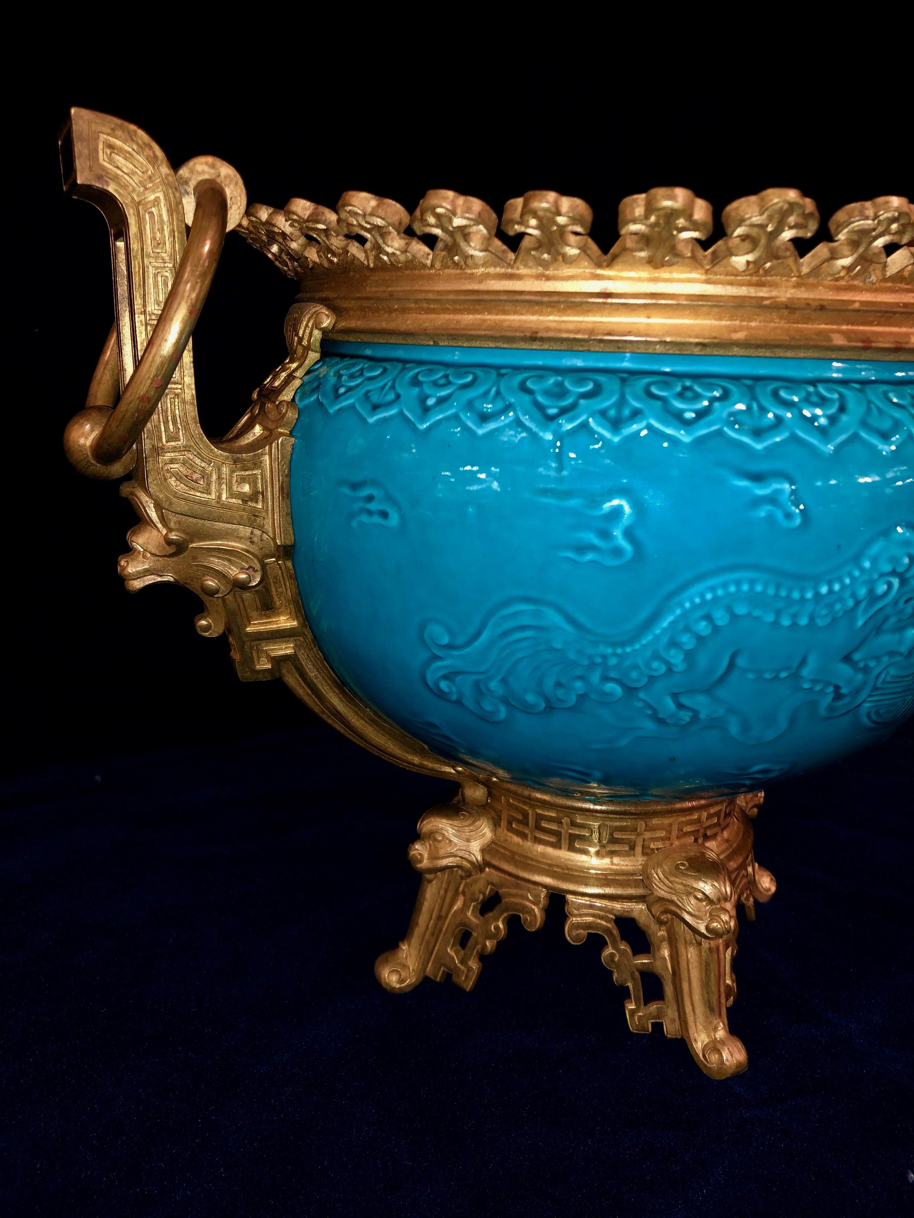 A marvelous French chinoiserie style earthenware dore bronze mounted turquoise blue ground planter or jardinière, attributed to Théodore Deck. The ceramic bowl is beautifully decorated with chinoiserie inspired decor which includes ruyi heads and