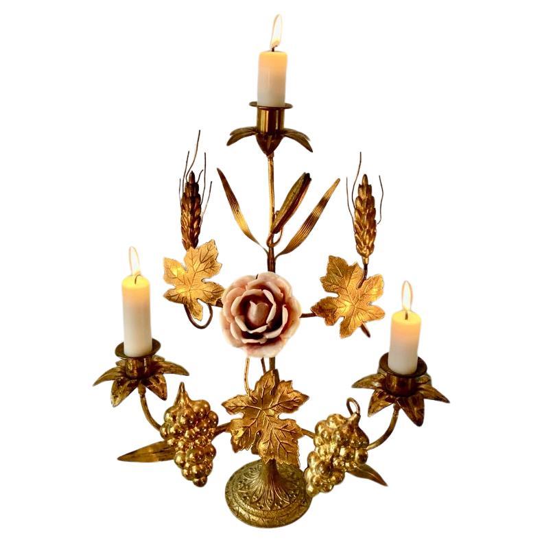 Antique French gilded brass church candelabra decorated with grapes, leafs, barley ears and a delicate porcelain rose in the middle. Despite its petite size, the candelabra can hold five candles. These antique French candelabras used to adorn the