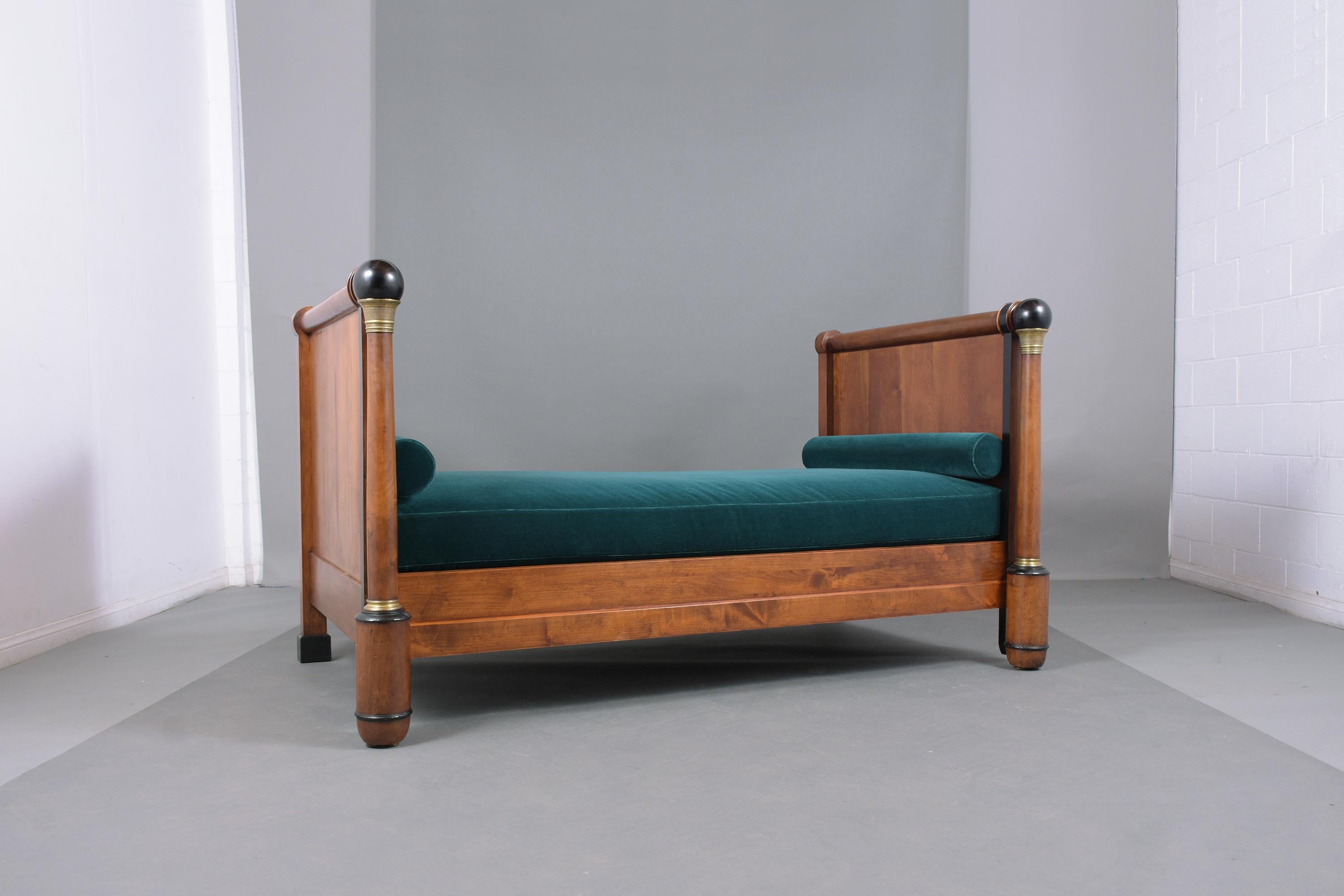 An extraordinary mid-19th century Empire daybed hand-crafted out of walnut wood and been professionally restored by our team of in-house craftsmen. This elegant daybed features straight headboard front columns with bronze ornaments, and molding