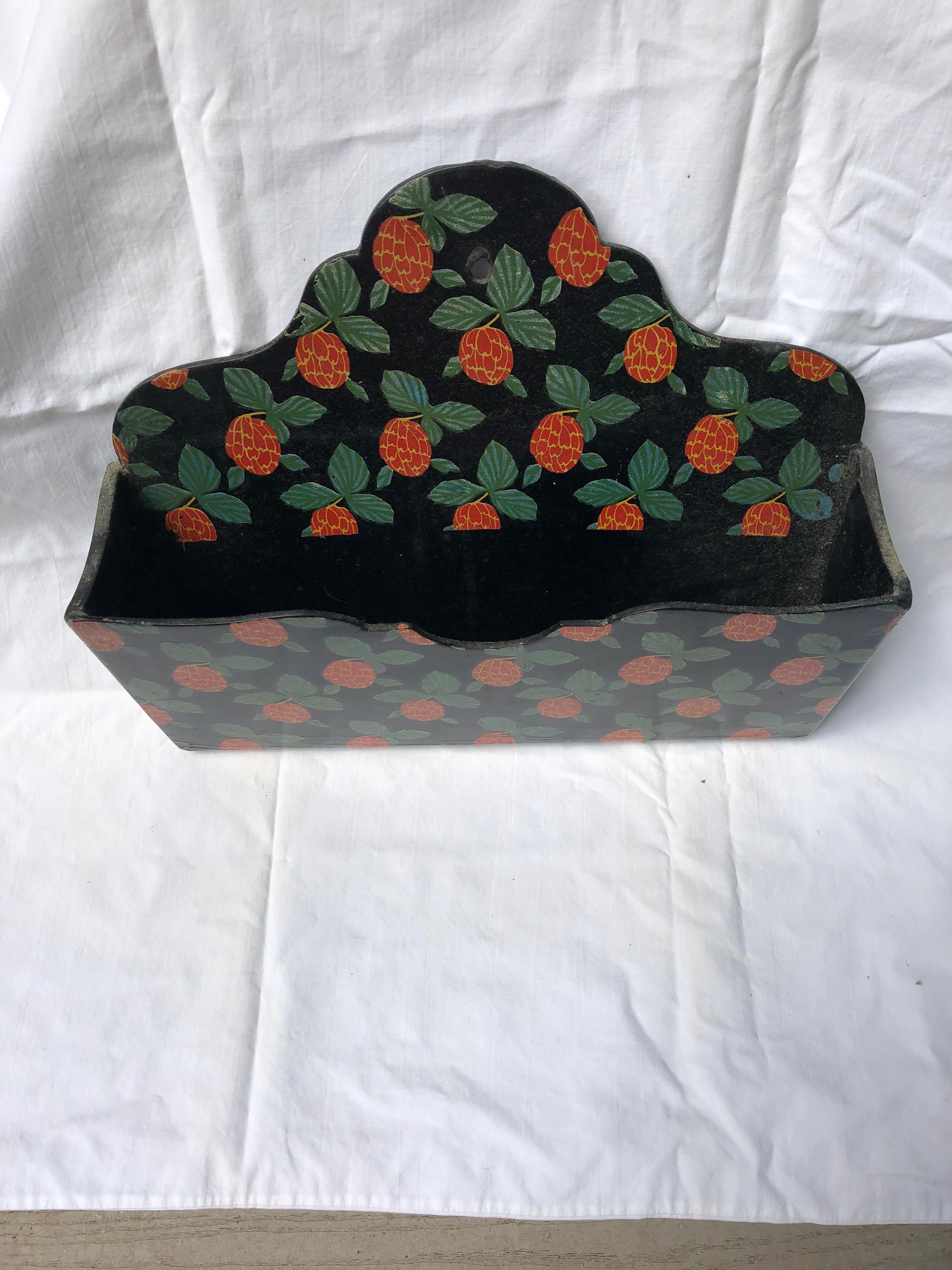 French papier-mâché letterholder or wall pocket with red painted kumquat decorations with green leaves and gold outlining on a black ground, circa 1870. There is a hole on the top to hang the piece.