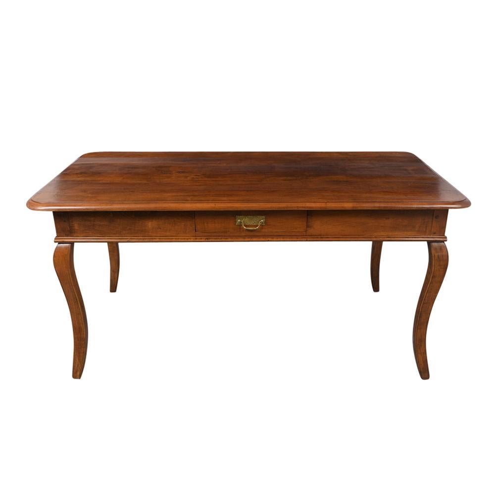 This Circa 1870's French Provincial Style Dining Table is made from solid cherry wood with its original walnut color staining and has a natural waxed finish. The table also features a single side drawer, hand-carved curved table legs, and is very