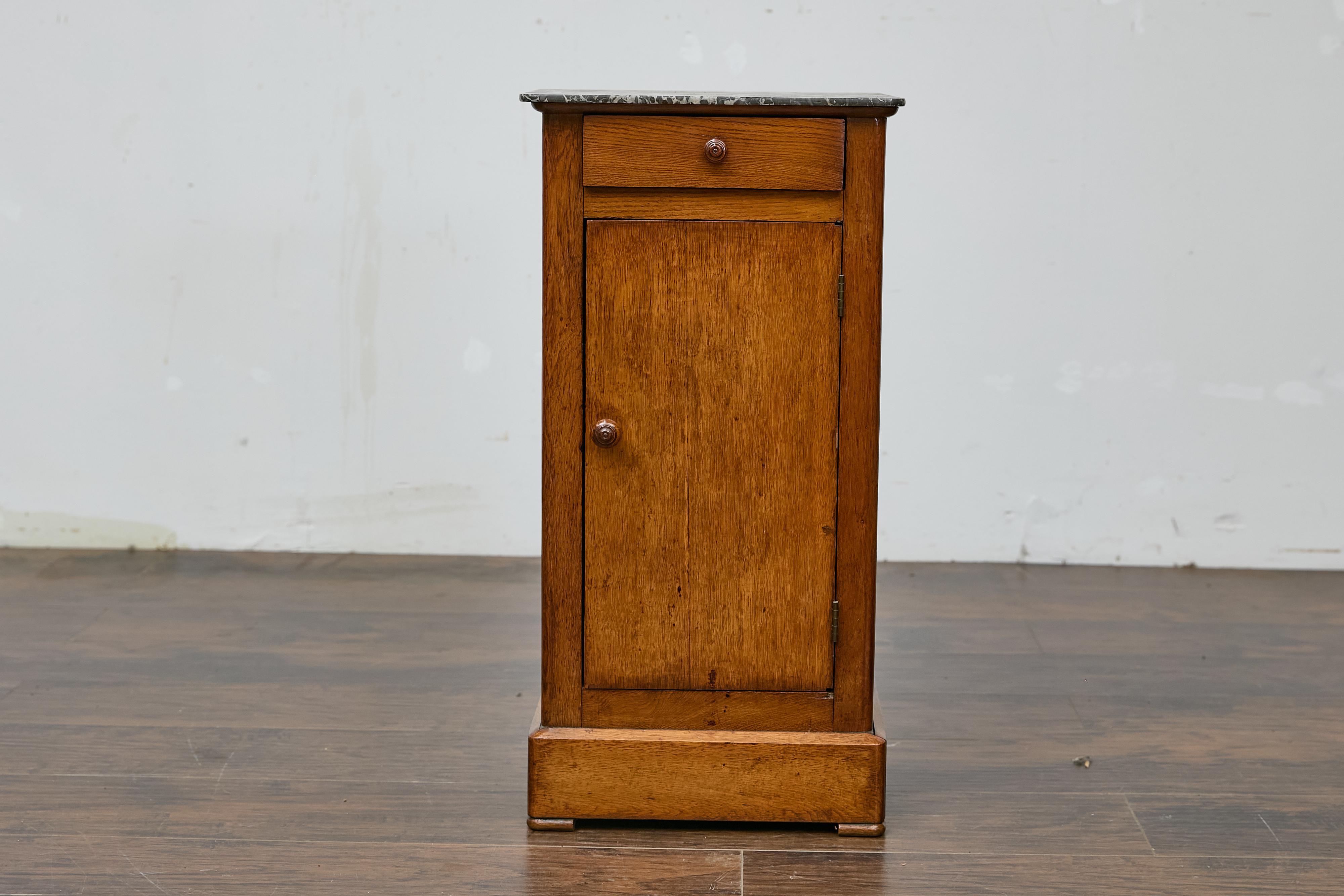A French Turn of the Century walnut small cabinet from circa 1900 with grey variegated marble top, single drawer over single door. This French Turn of the Century walnut cabinet, crafted around 1900, boasts a refined yet understated elegance. Topped