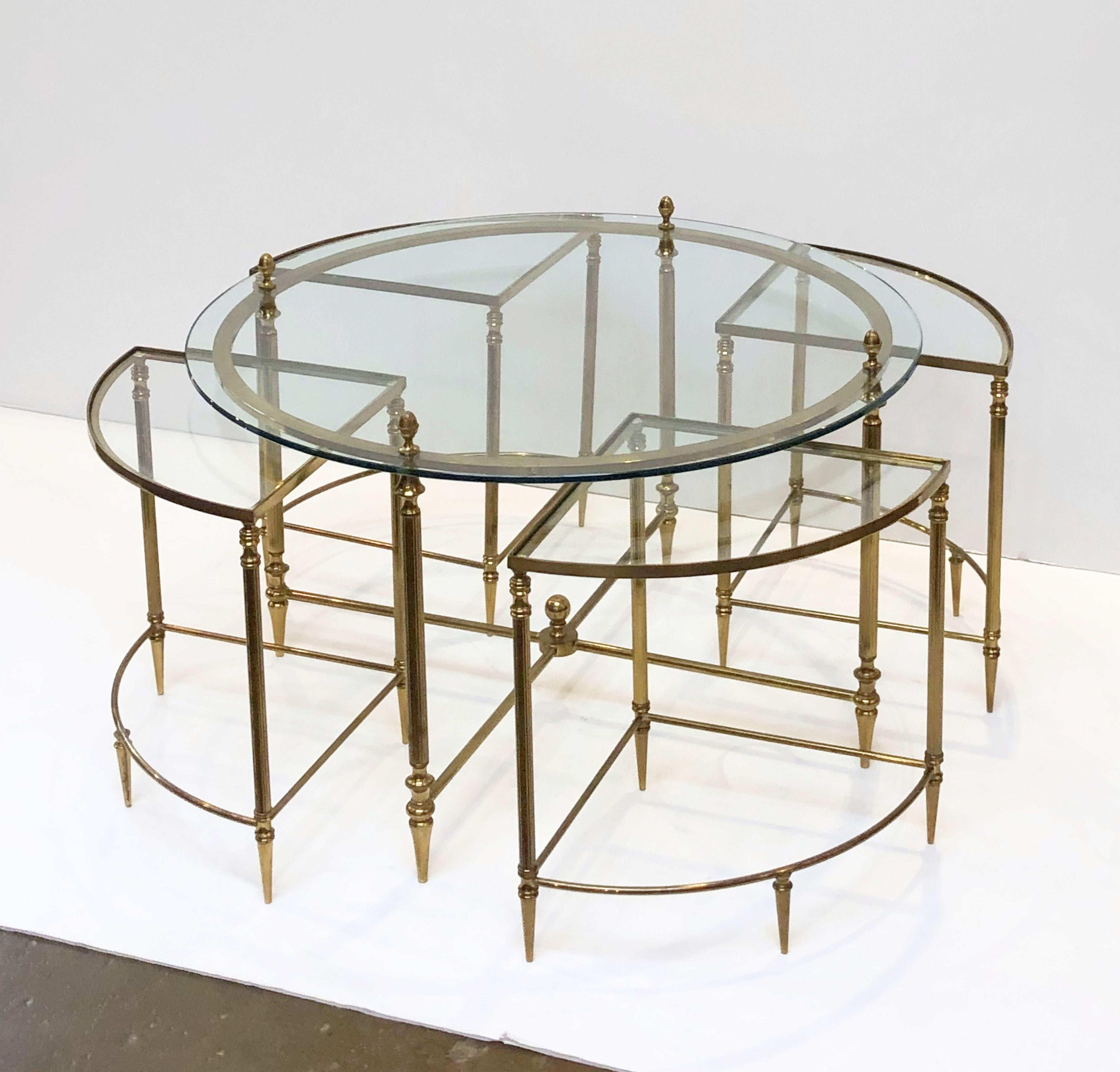 A fine French circular low cocktail (or coffee) table of brass and glass featuring a round top table with four wedge-shaped nesting under-tables.

The 'gigogne' tables consist of a set of small lightweight tables that fit under the larger table to