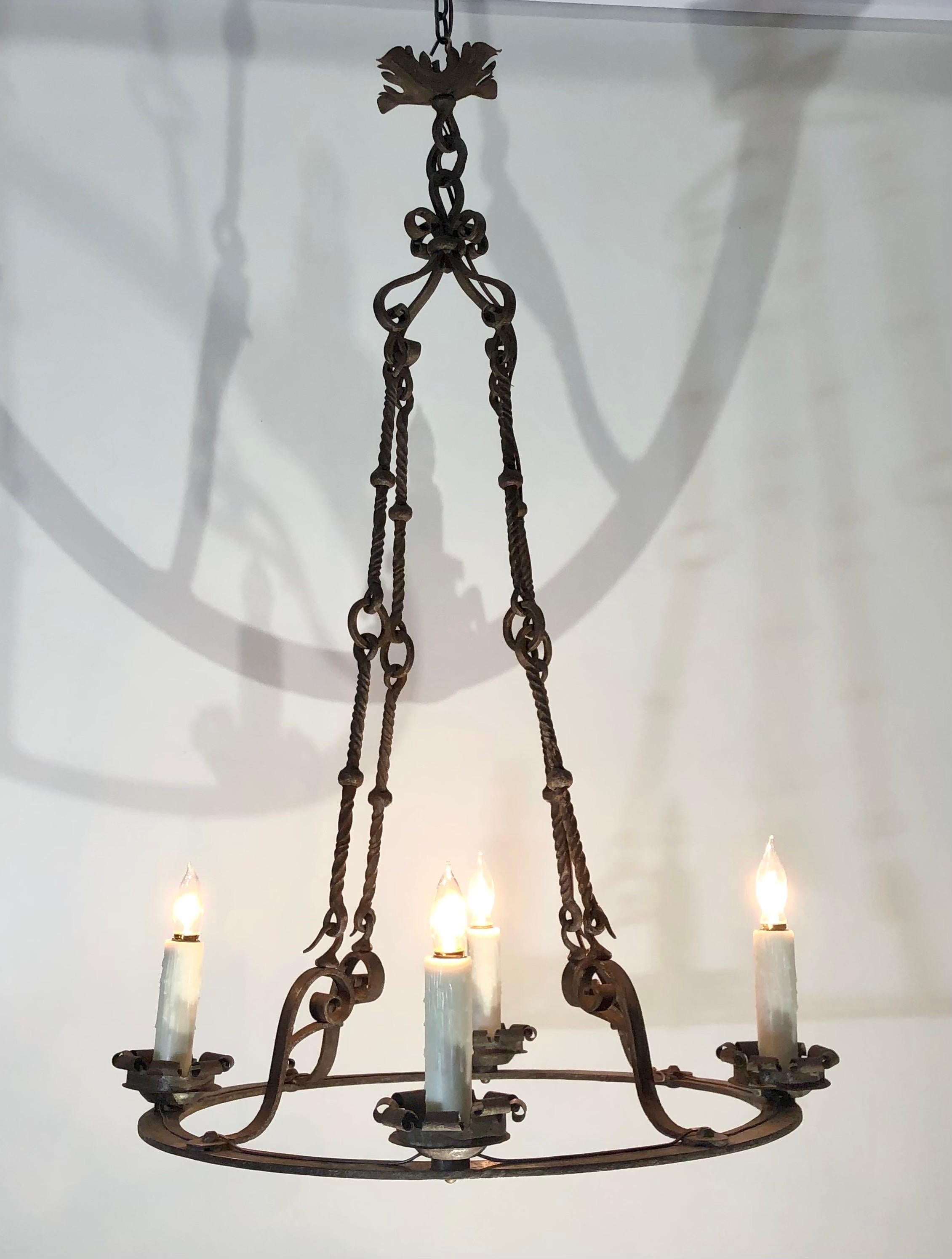 Dieser französische kreisförmige Kronleuchter aus handgeschmiedetem Eisen mit vier Lichtern wurde im 19. Jahrhundert hergestellt.  Die  Der runde, handgeschmiedete Eisenring hat vier schmiedeeiserne Bögen und war ursprünglich eine Kerze.   Der