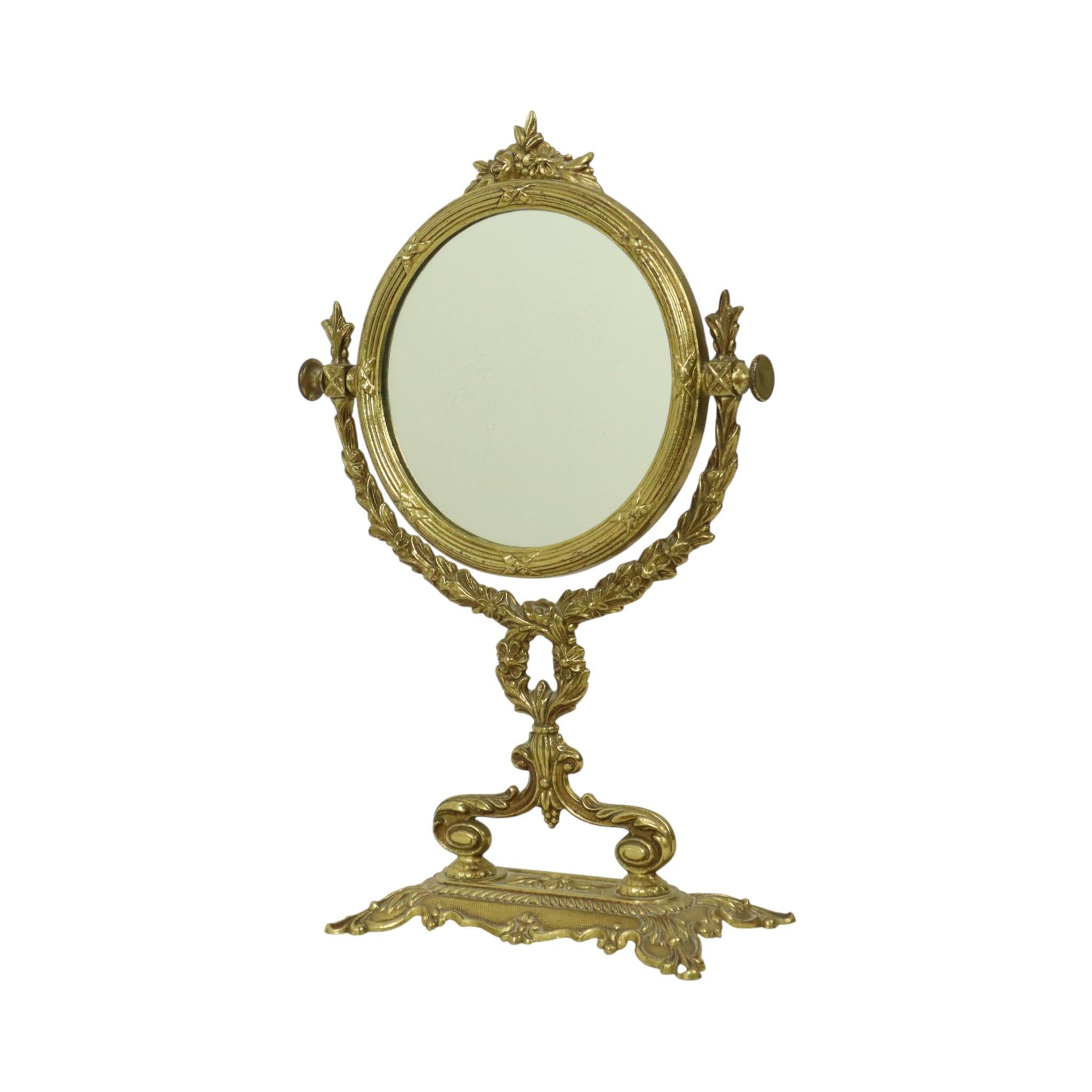 Miroir de table inclinable classique français, miroir de vanité en laiton ou en cuivre jaune, entièrement de style baroque, France, vers le milieu du XXe siècle.

Le verre du miroir est taché de façon décorative, une caractéristique commune aux
