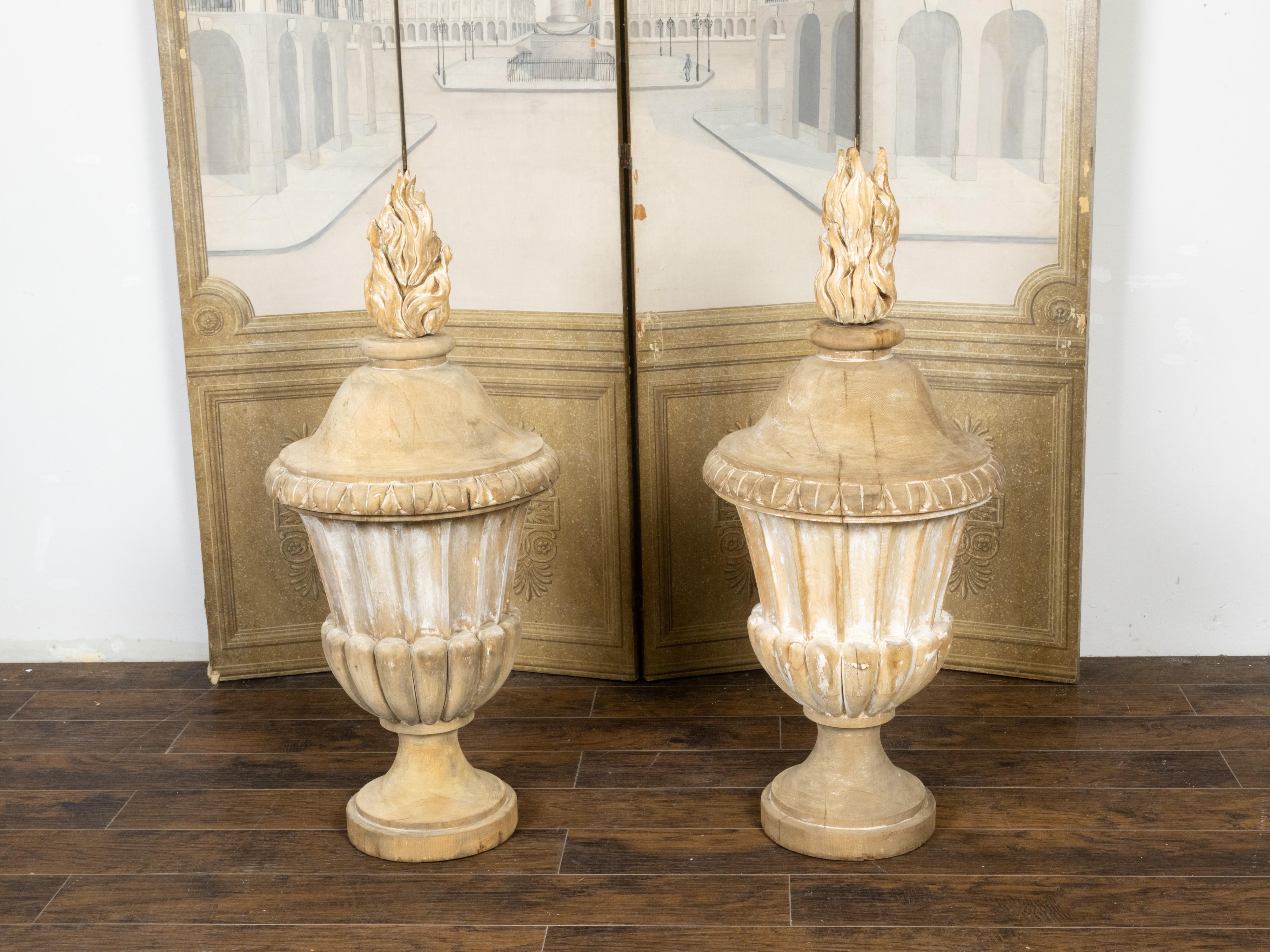 Ein übergroßes Paar geschnitzter französischer Feuertöpfe aus Holz aus dem 19. Jahrhundert, mit oberen Flammen und kannelierten Vasen. Dieses Paar Pots à Feu (übersetzt Feuertöpfe, Feuerurnen), das im 19. Jahrhundert in Frankreich entstand, erinnert