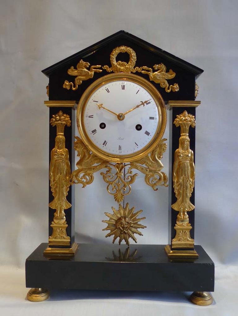 A French Directoire ormolu mounted black marble portico clock of Egyptian temple form. Set upon ormolu toupee feet with a rectangular black marble base. Black marble columns rise up to a triangular marble tympanum. The well made marble case applied