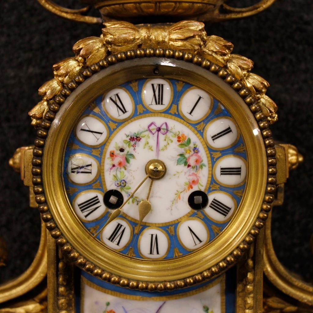 French clock from the mid-20th century. Object in bronze and brass gold is chiselled, adorned with hand-painted ceramic elements with very pleasant floral decorations. Rear door with glass to be replaced (see photo), mechanism not working, to be