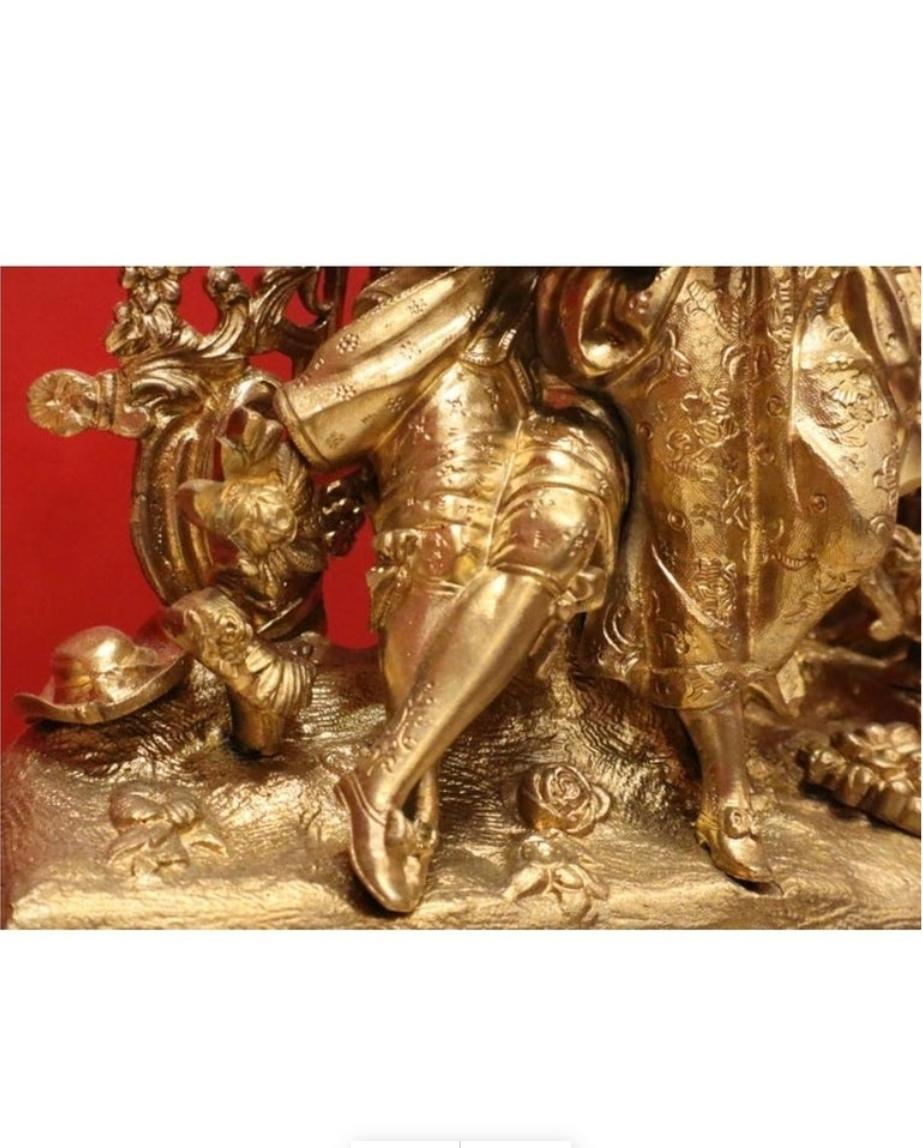 Französische Kaminsimsuhr aus vergoldeter Bronze (Ormolu) aus dem späten 19. Jahrhundert im Stil des Rokoko. Diese trapezförmige Uhr wird von vier Schneckenfüßen getragen, der untere Teil ist symmetrisch mit Rokoko-Motiven verziert. 

Sie wird von