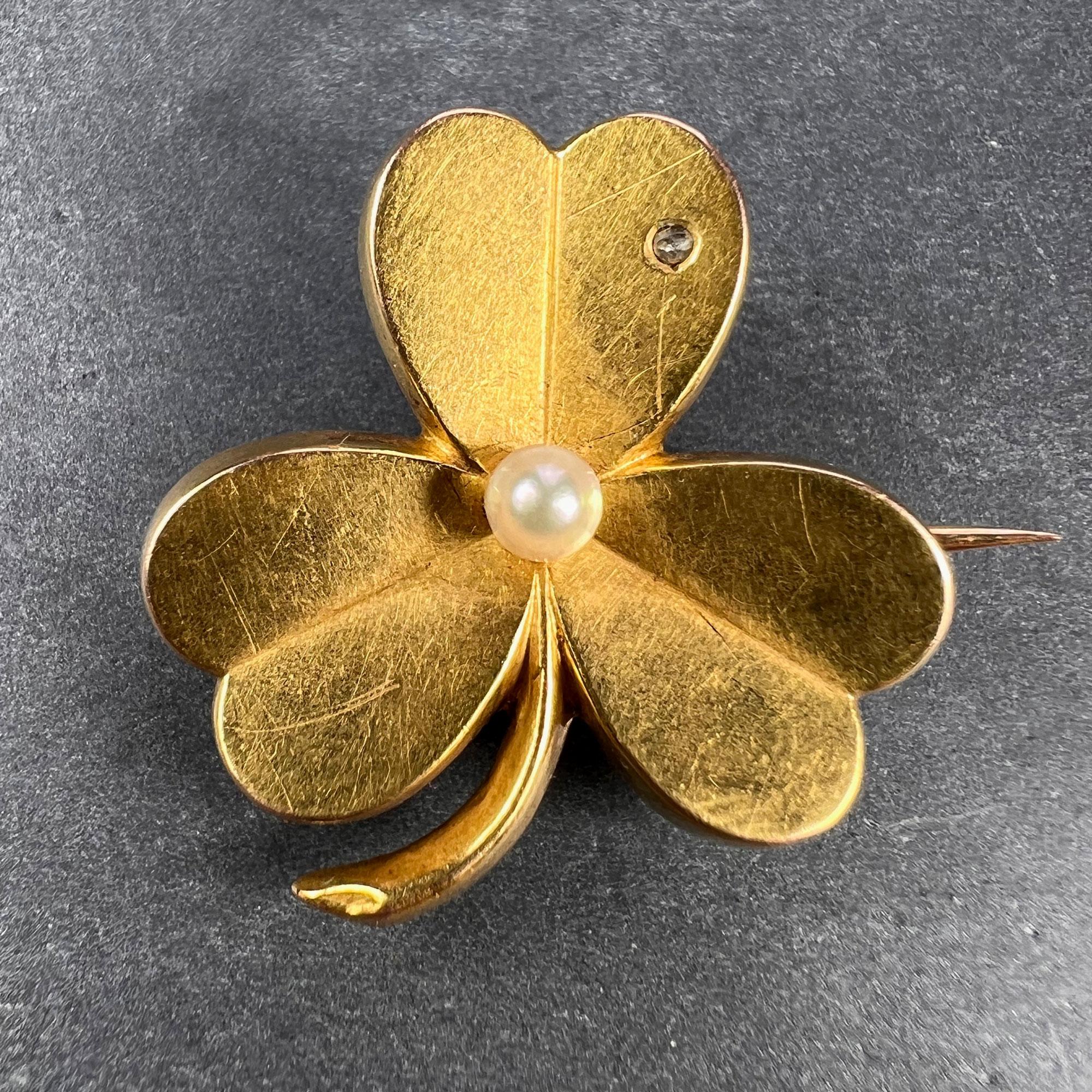 A French 18 karat (18K) yellow gold brooch with pendant fitting designed as a clover or shamrock set with a rose-cut diamond weighing approximately 0.03 carats and a natural pearl measuring 3.5mm. Stamped with the eagle mark for 18 karat gold and