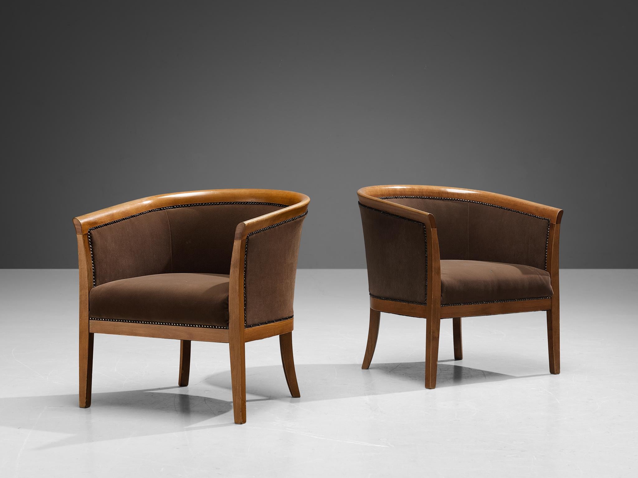 Pair of club chairs, brown fabric, beech, brass, France, 1940s.

These classically sculpted armchairs feature seatings that are designed as a shell, which embraces the sitter wonderfully. The curvaceous lines of the frame are further emphasized by