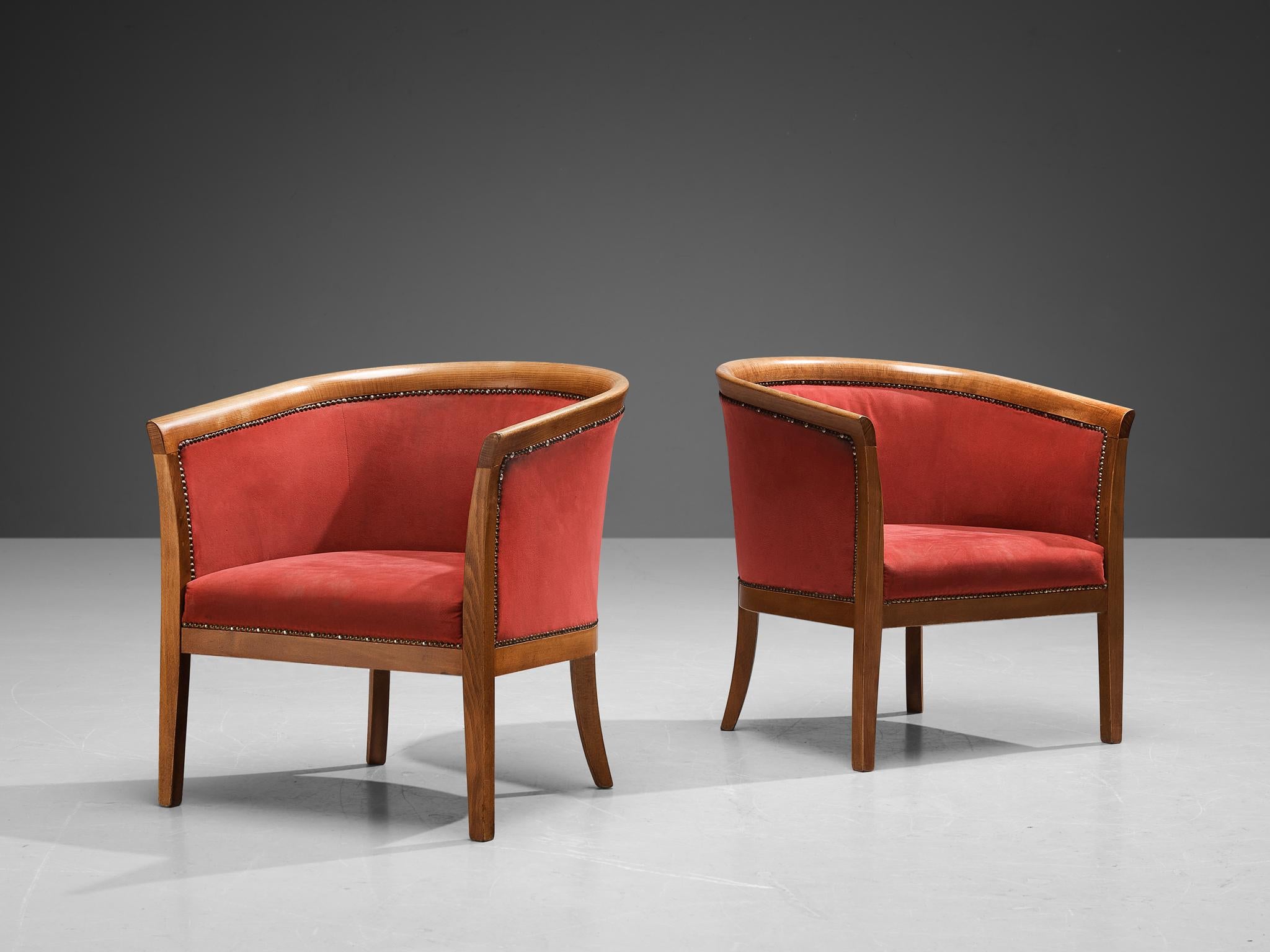 Club chairs, red fabric, beech, brass, France, 1940s.

These classically sculpted armchairs feature seatings that are designed as a shell, which embraces the sitter wonderfully. The curvaceous lines of the frame are further emphasized by the brass