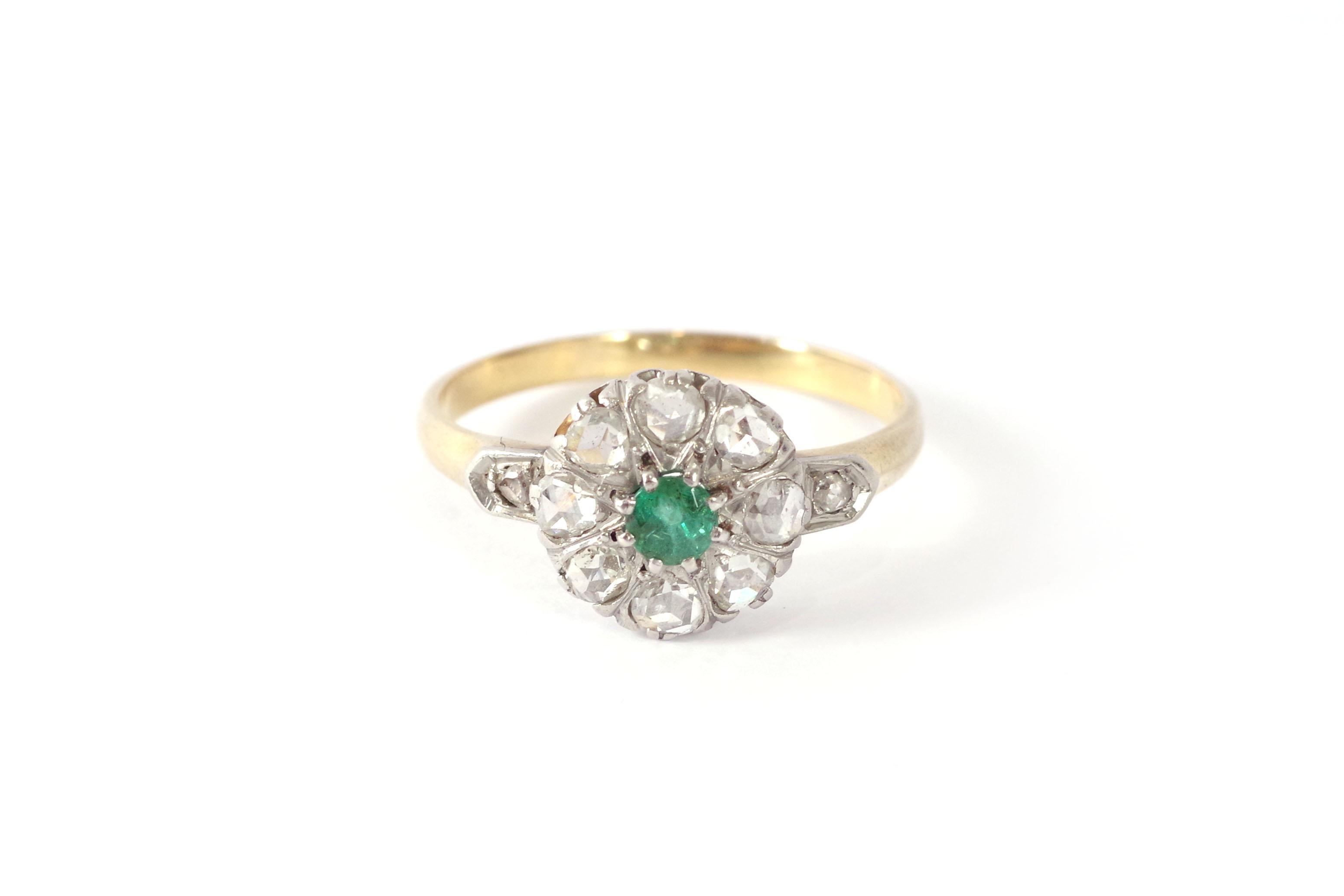 French cluster emerald ring in 18 karat pink gold and platinum. Antique cluster ring with a round-cut emerald set with eight claws. The emerald is surrounded by eight Dutch rose-cut diamonds. Each shoulder of the ring is also set with a diamond.