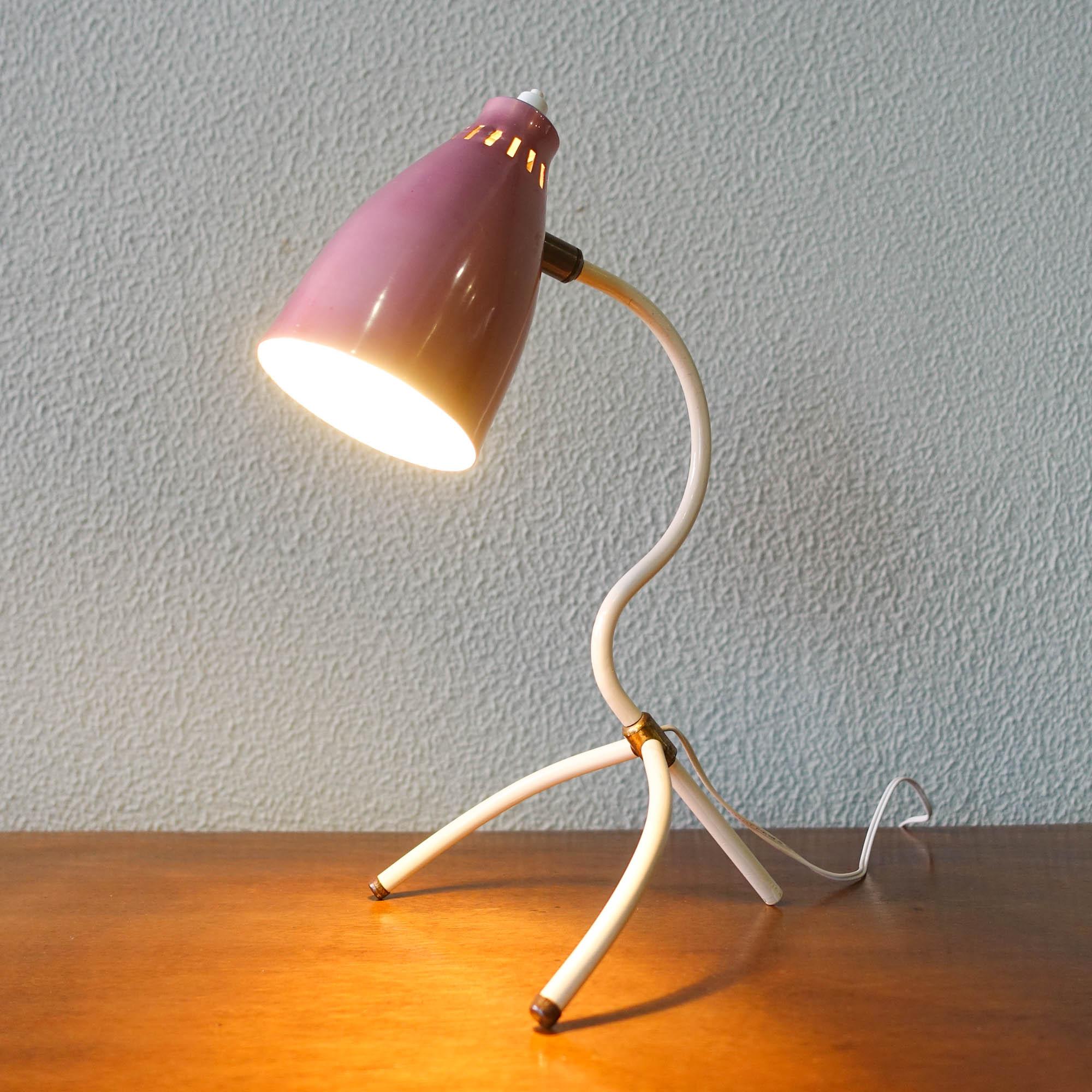 This table lamp was designed and produced in France during the 1950s. It is a typically 50s French 'Cocotte' design.
Metal tripod structure with bended arm, orientable pink lacquered and perforated aluminum shade. Brass joints.
Original condition,