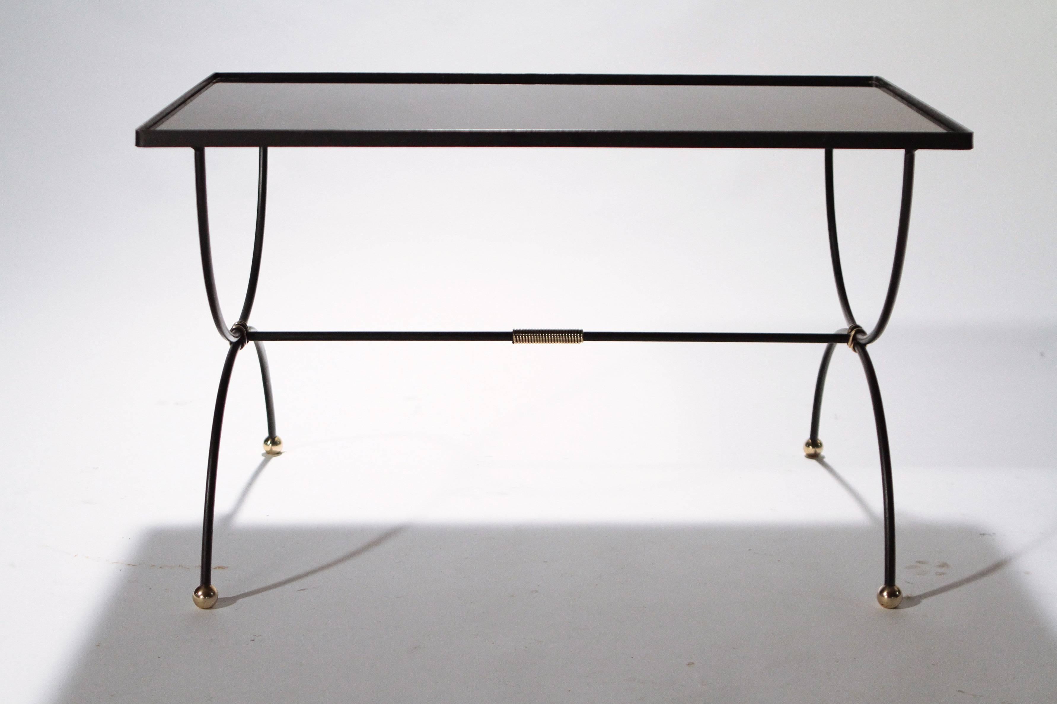 Grace your home with the true elegance of this black iron with brass details coffee table, attributed to Jacques Adnet. Featuring an opaline black top, and beautiful brass details, it will add character to your home and make a gracious compliment to