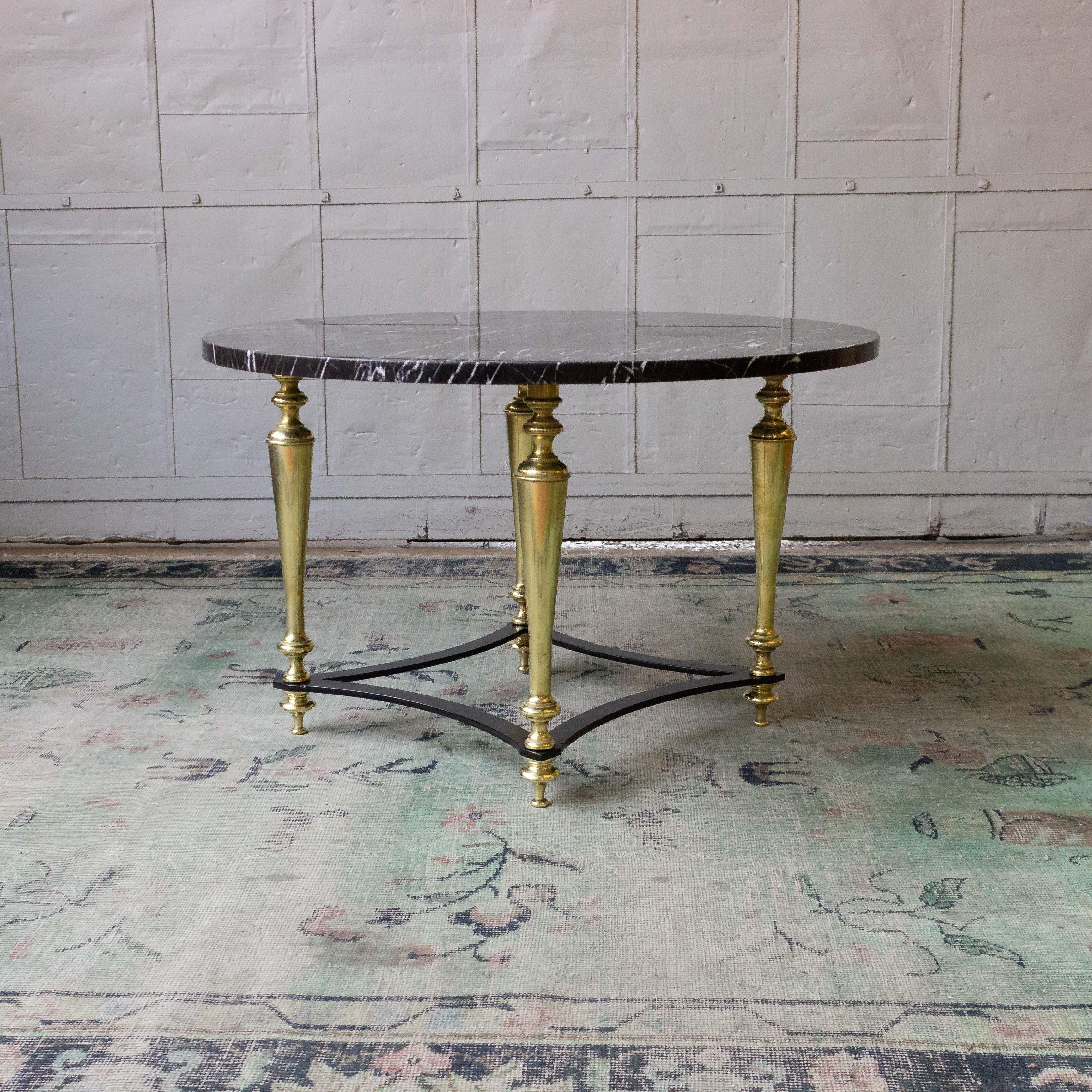 Small round coffee table, the base is a combination of turned brass legs joined by a flat iron stretcher. The top is a dark grey marble with white veining. The table has recently been polished as well as the marble, French, 1940s.