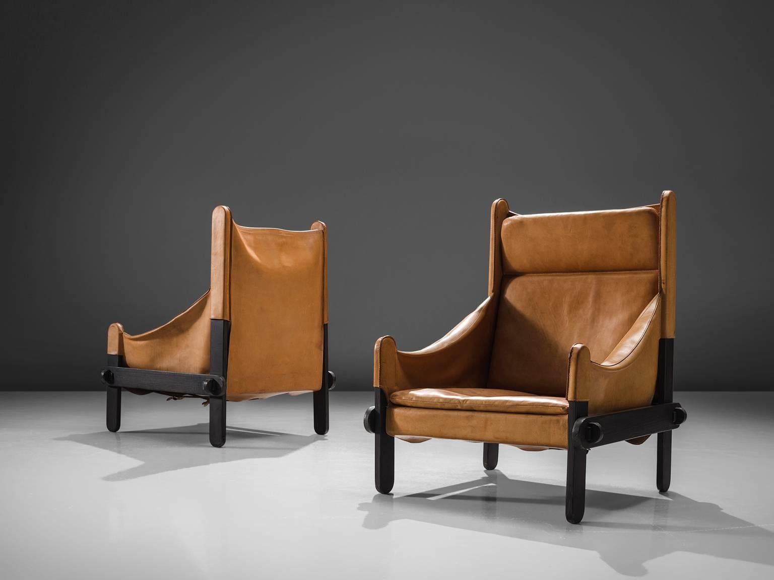 Armchairs, leather, wood, France, 1950s. 

These lounge chairs holds a solid crafted frame with decent wood details/joints. The design is original and rare and features a completely straight high back and sloping armrests that end upwards in a point